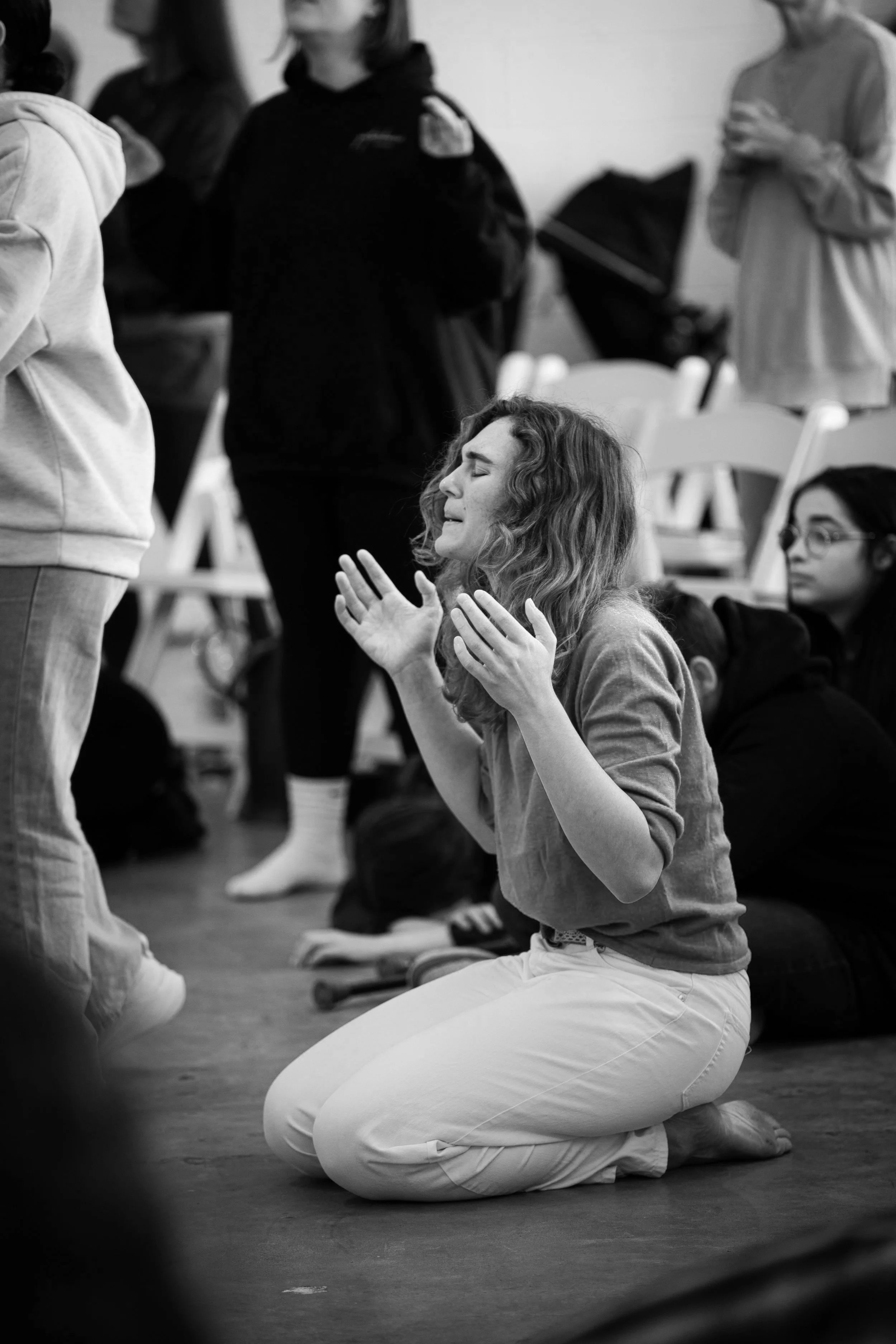 A group of people, some kneeling, others standing, in a room, possibly praying or meditating.