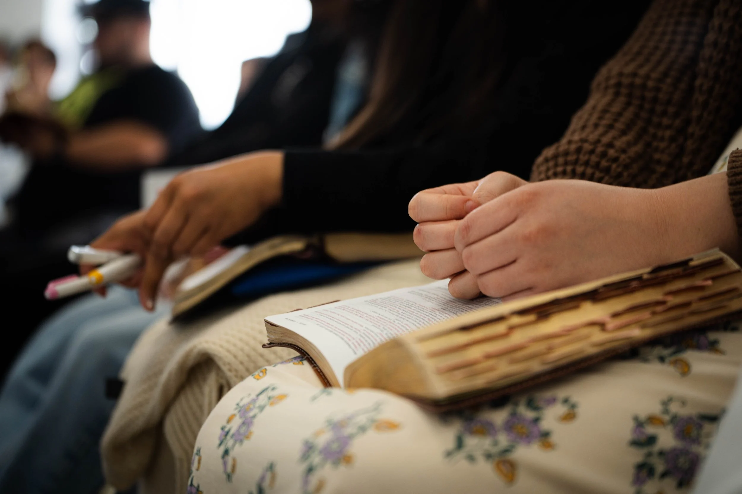 People sitting in a row, holding notebooks and pens, attending an event or a class.
