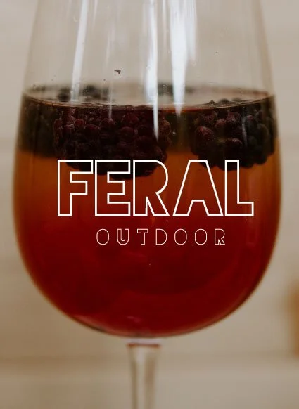 A glass of berry-infused drink with text 'FERAL OUTDOOR' overlaid on it.
