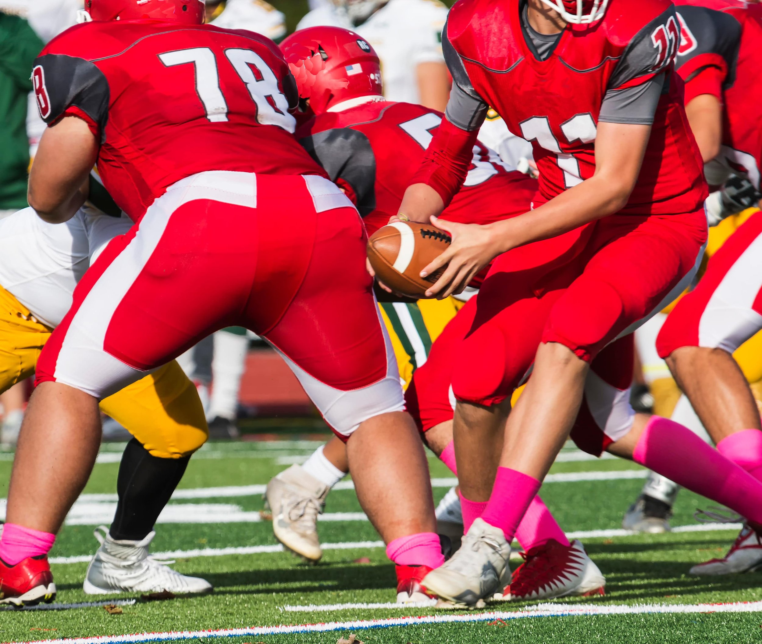 Football players, in uniform, training on a football field.