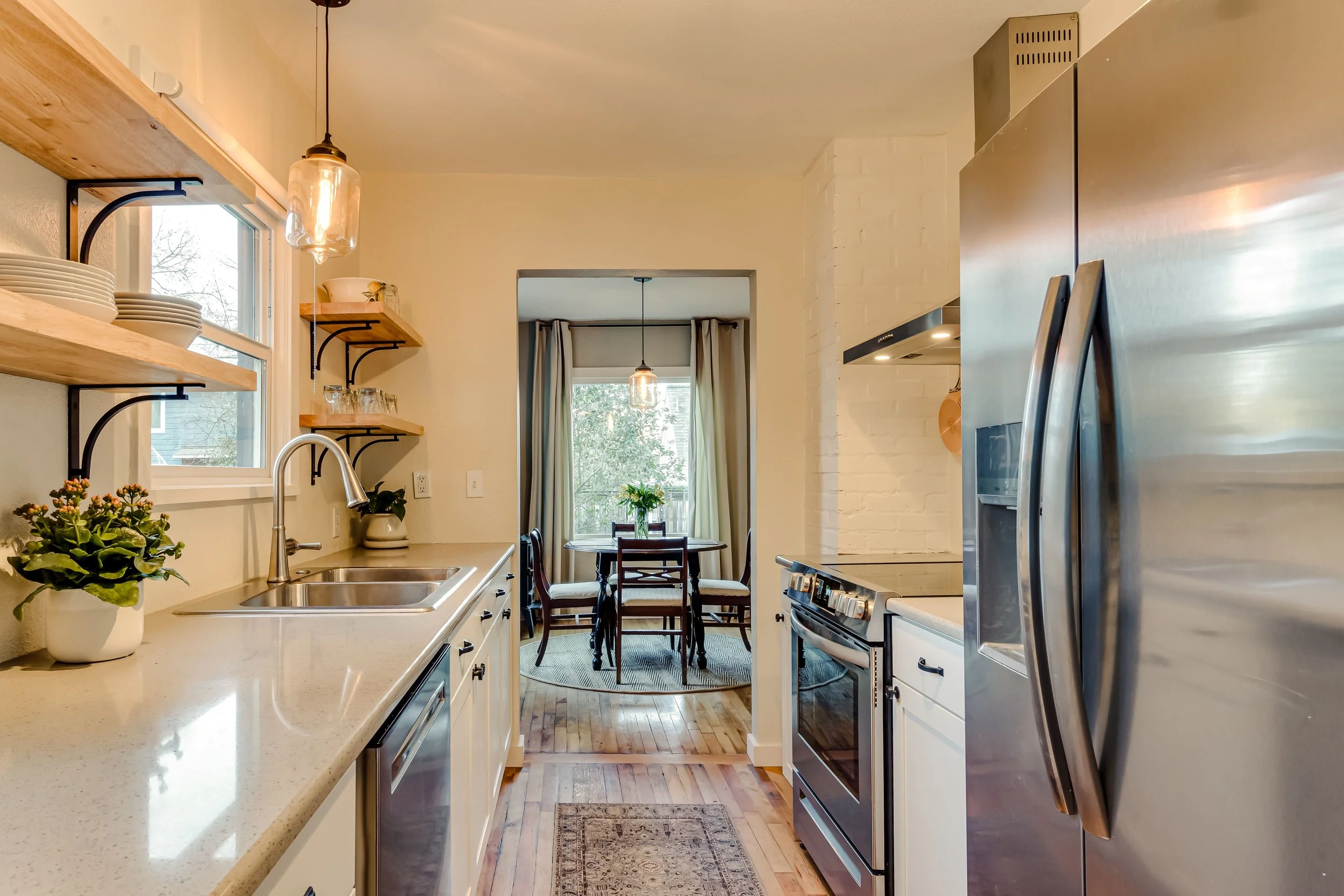 Modern kitchen with stainless steel appliances, open shelving, and a small dining area.
