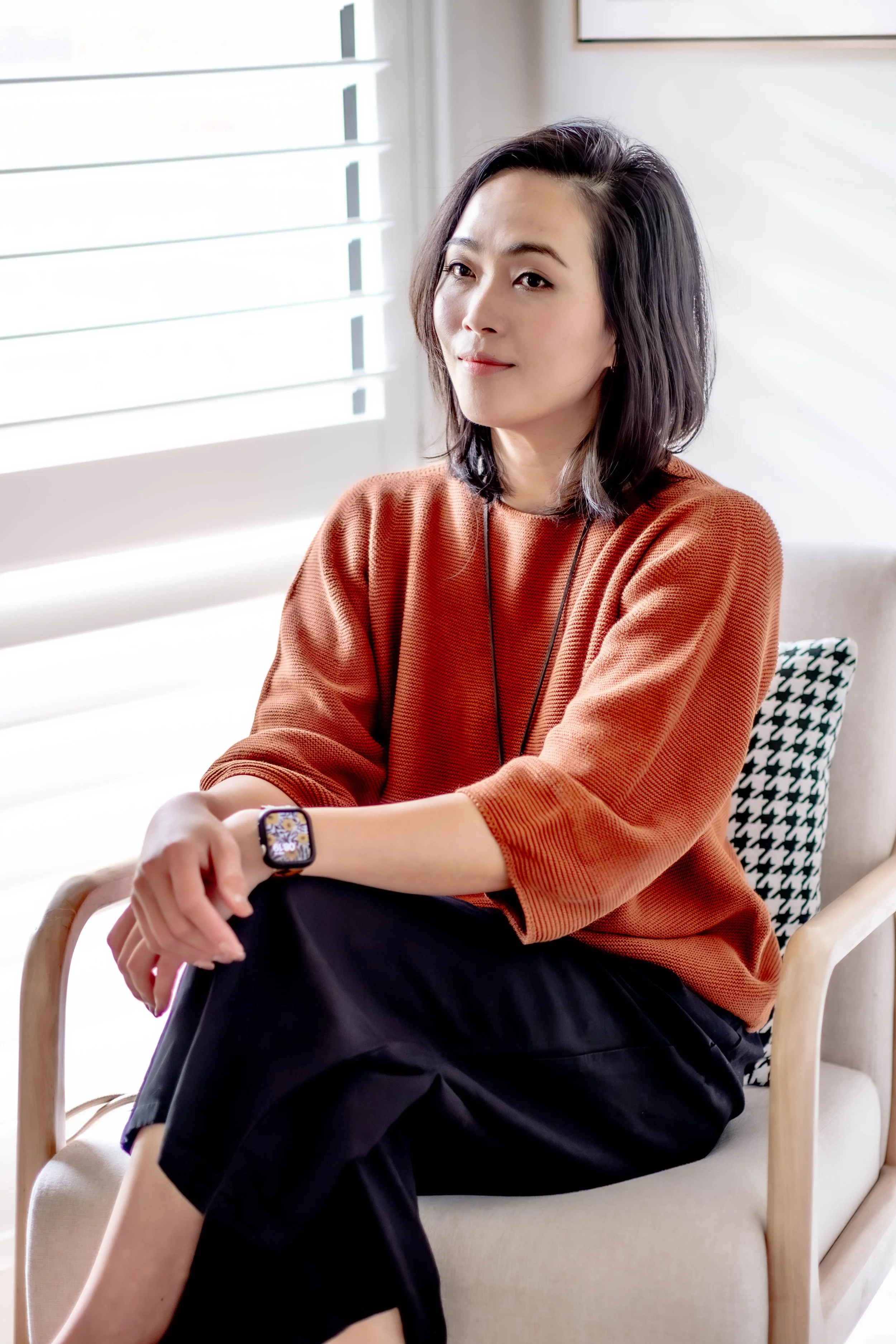 Interior designer/decorator/stylist, Anna Manson seated in a cosy armchair at her home studio, bathed in soft natural light – Leafy Interiors.
