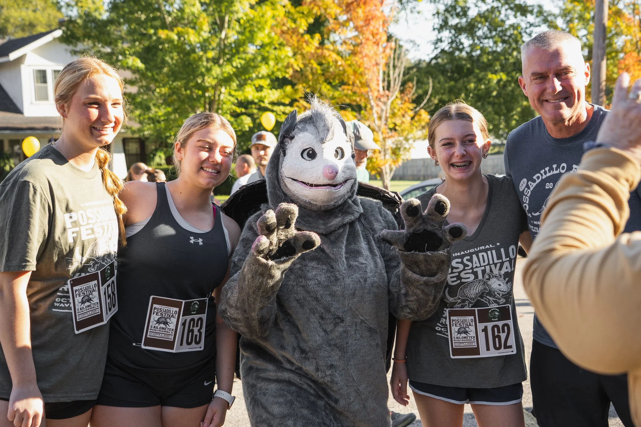 Group of four young women and a man posing for a photo with the possadillo mascot at the possadillo festival in Waverly Tennessee 