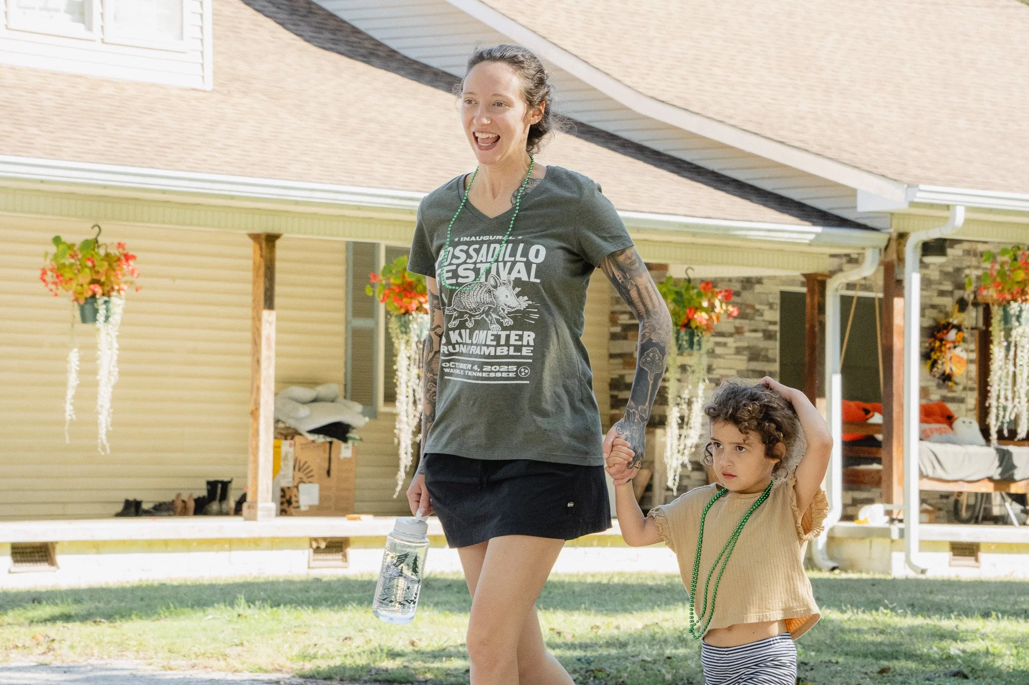 A woman and a young girl walking hand in hand outdoors at the Waverly Possadillo Festival