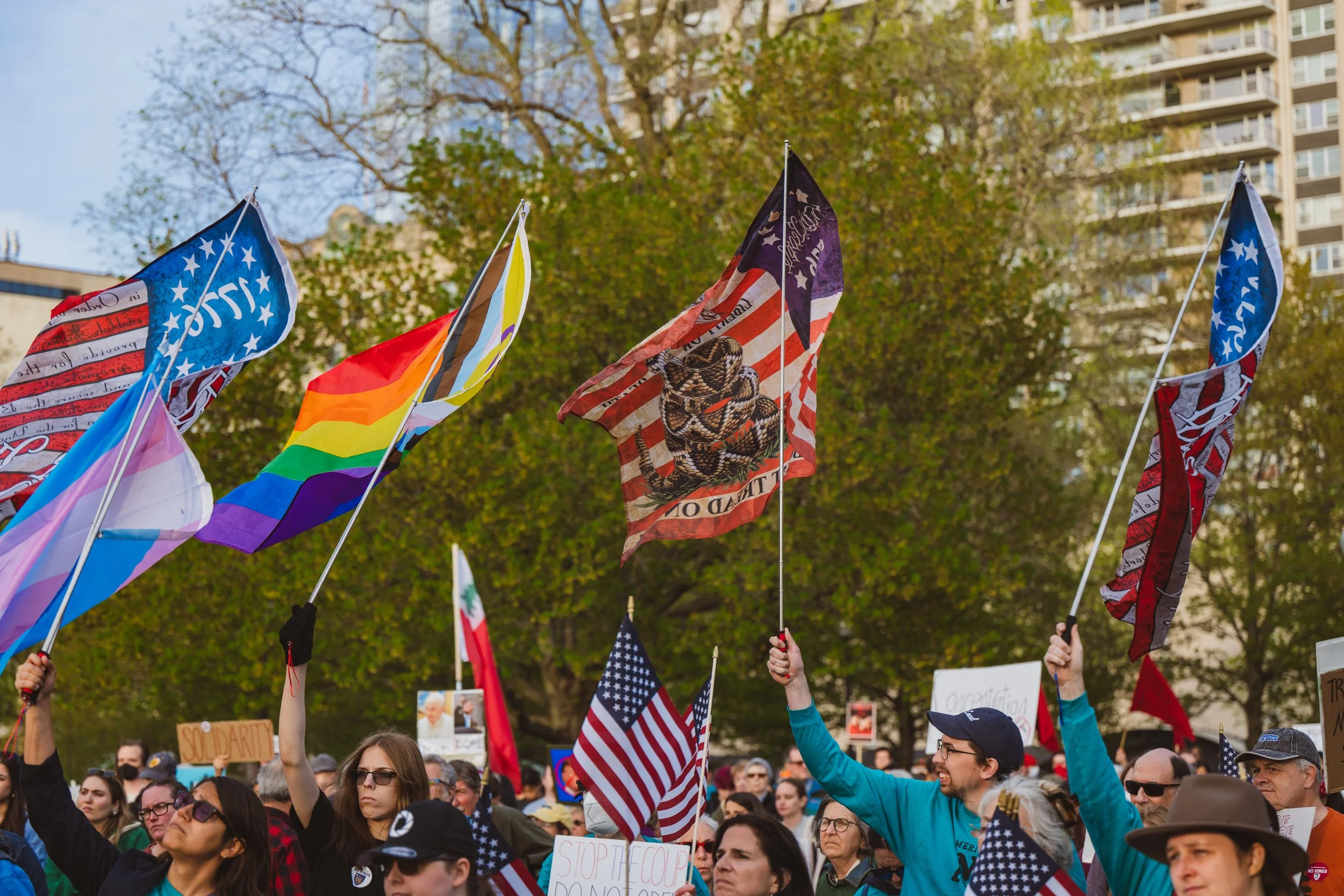 Mass 50501 at Boston’s 2025 May Day Rally holding various flags like the American flag and LGBTQ flag.