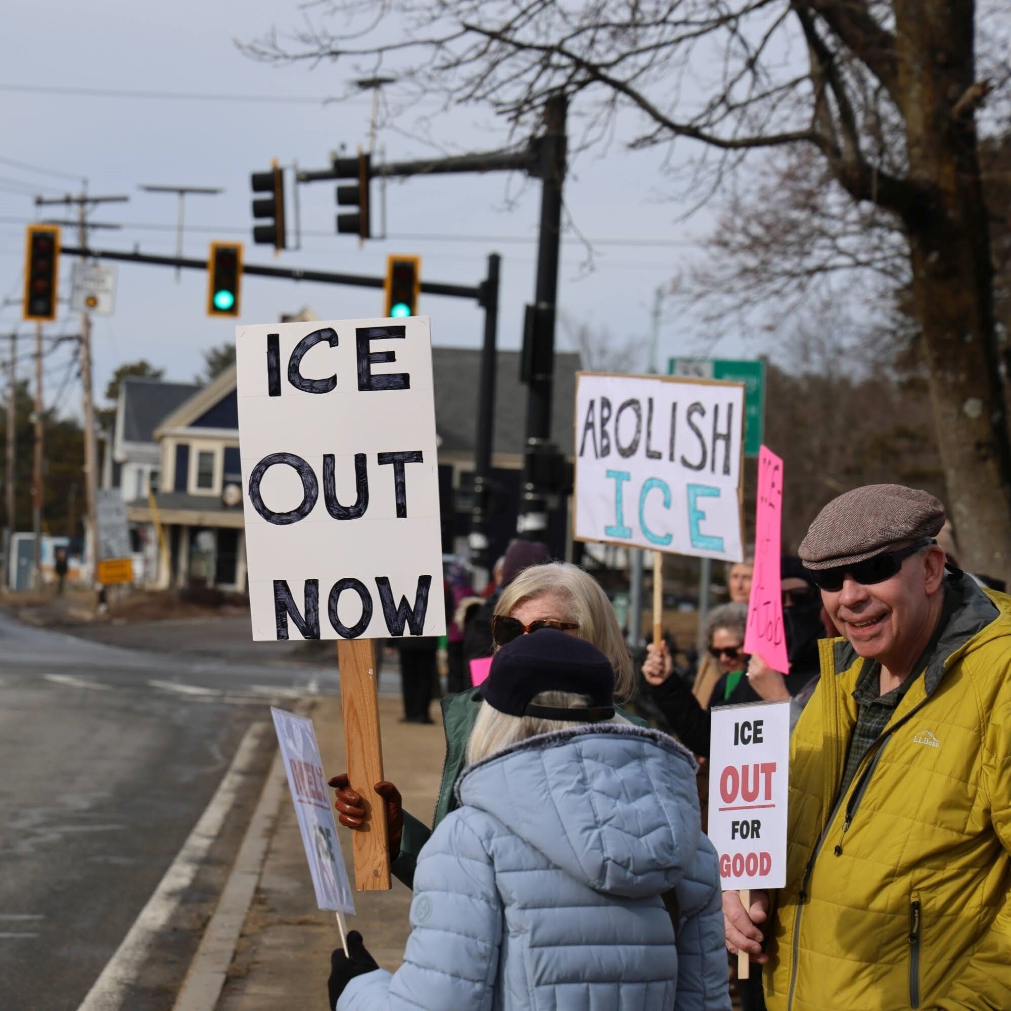 Photo via Mass 50501 volunteer showing the back of a person holding a sign that reads "ICE OUT NOW".