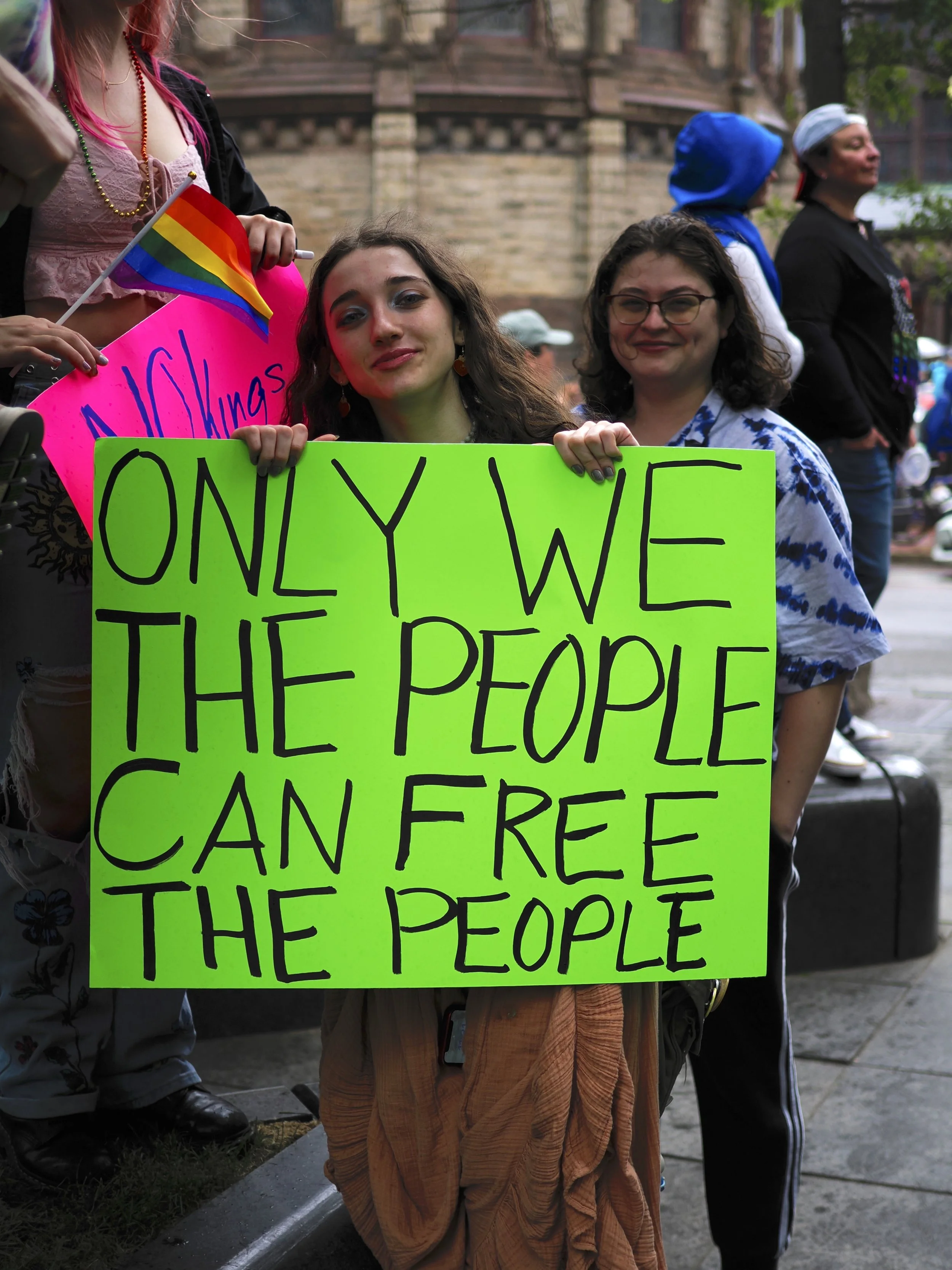 A person holding a neon-green sign saying “Only We the People can Free the People.”