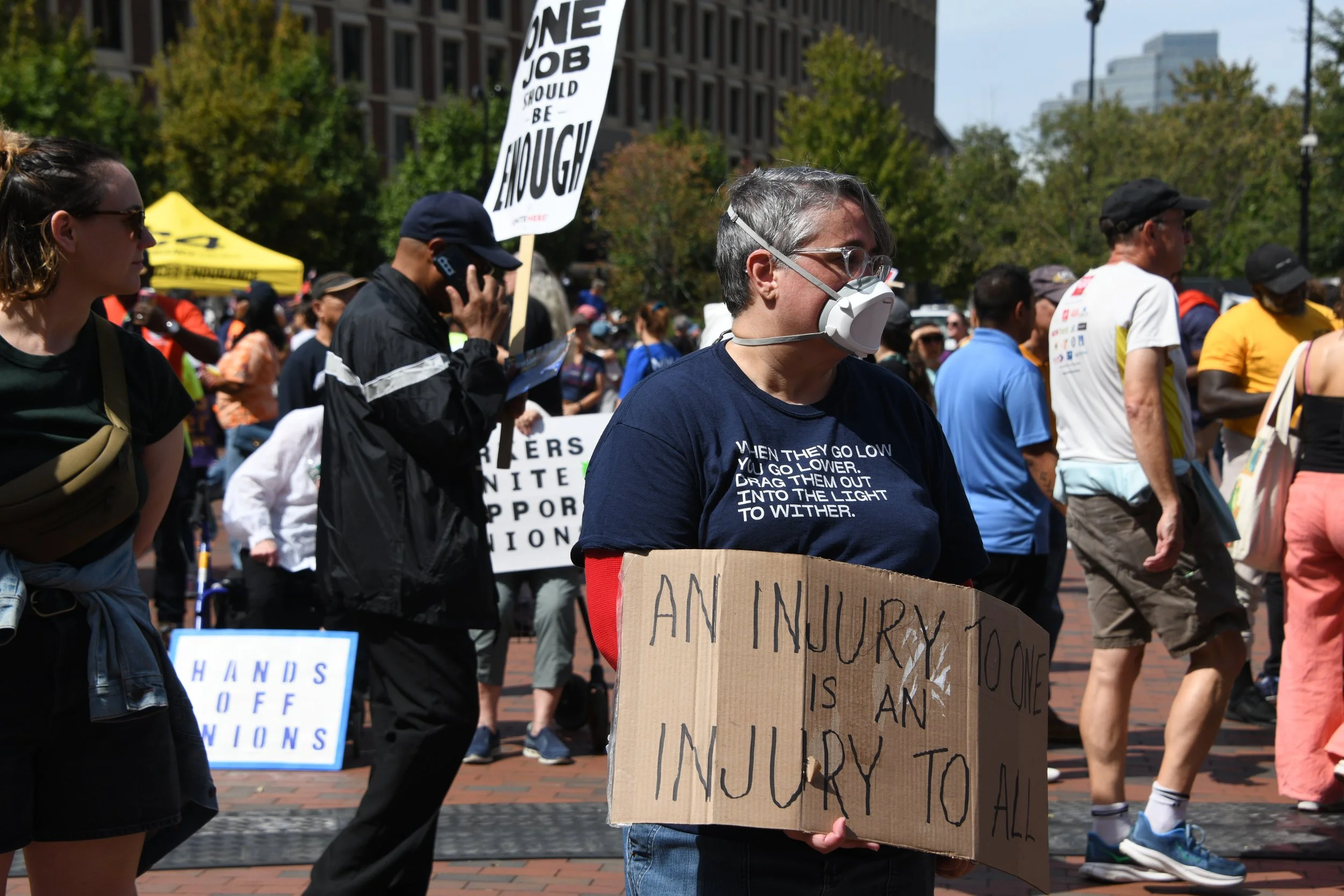 Protestors at the federal building holding signs. One says "An injury to one is an injury to all." Another says "Hands off Unions"