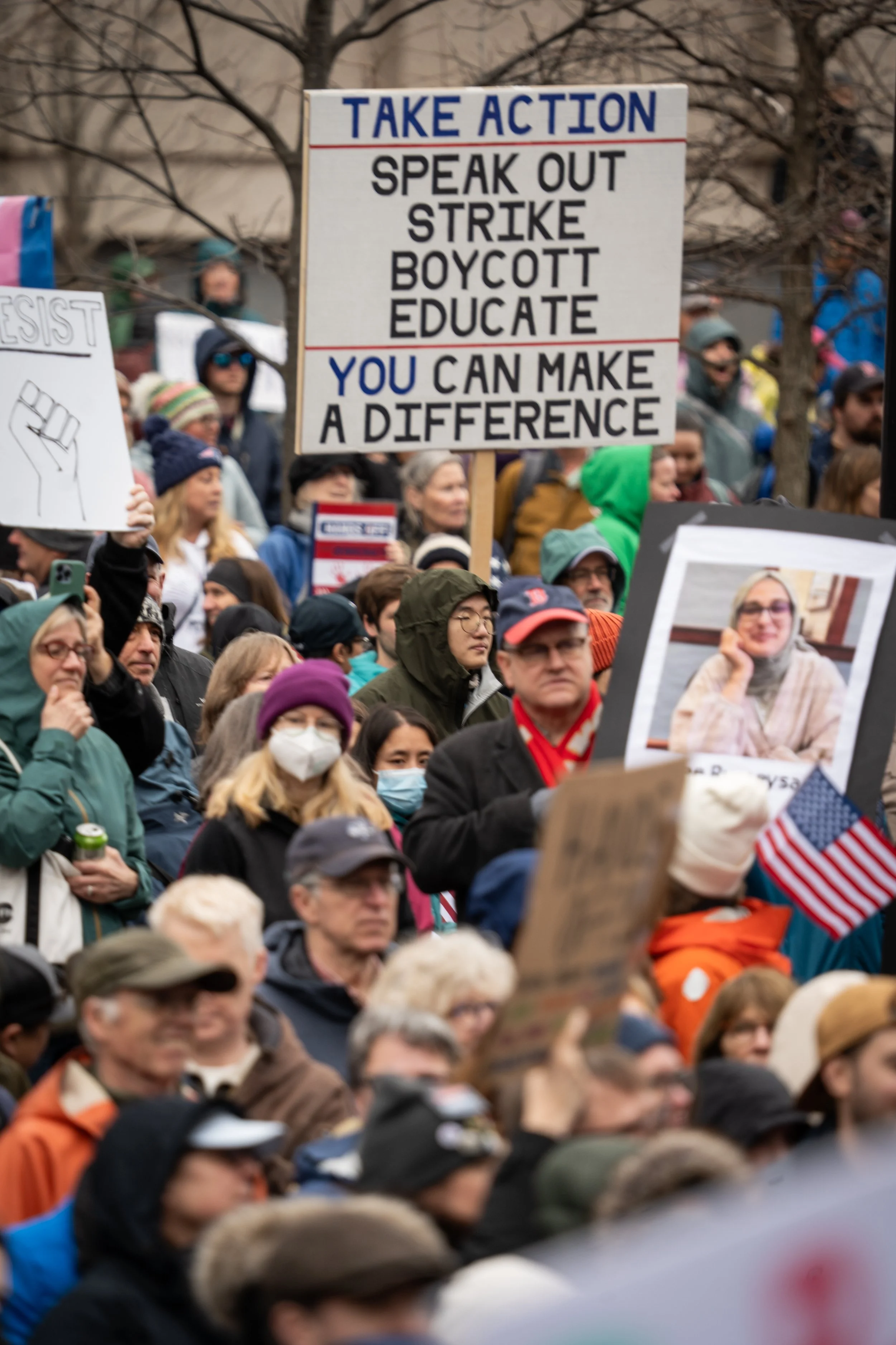 A group of protestors, focusing on the sign saying "Take Action. Speak Out. Strike. Boycott. Educate. You can make a difference"