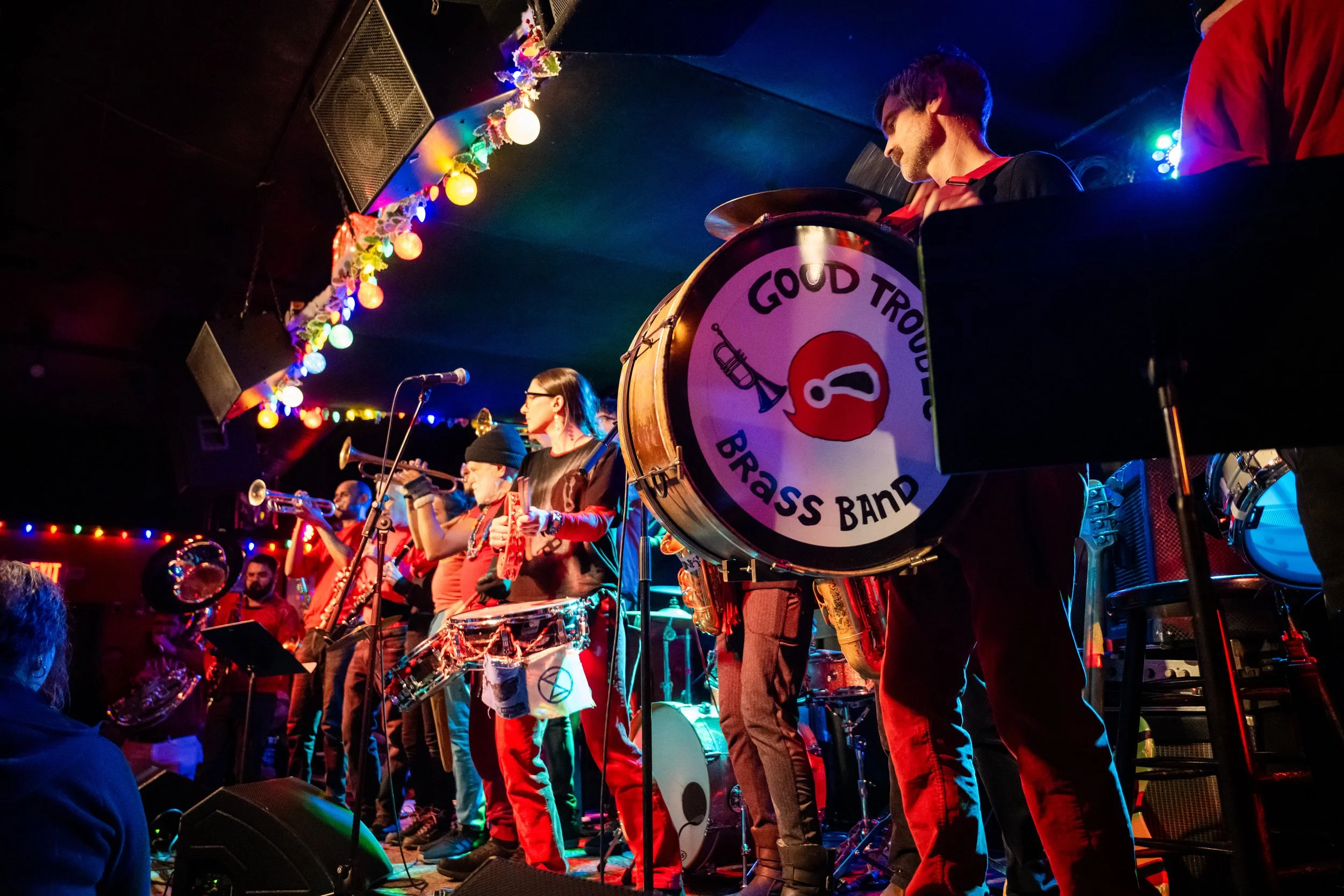A brass band performing on stage at the Burren in Somerville, with “Good Trouble Brass Band” written on the bass drum.