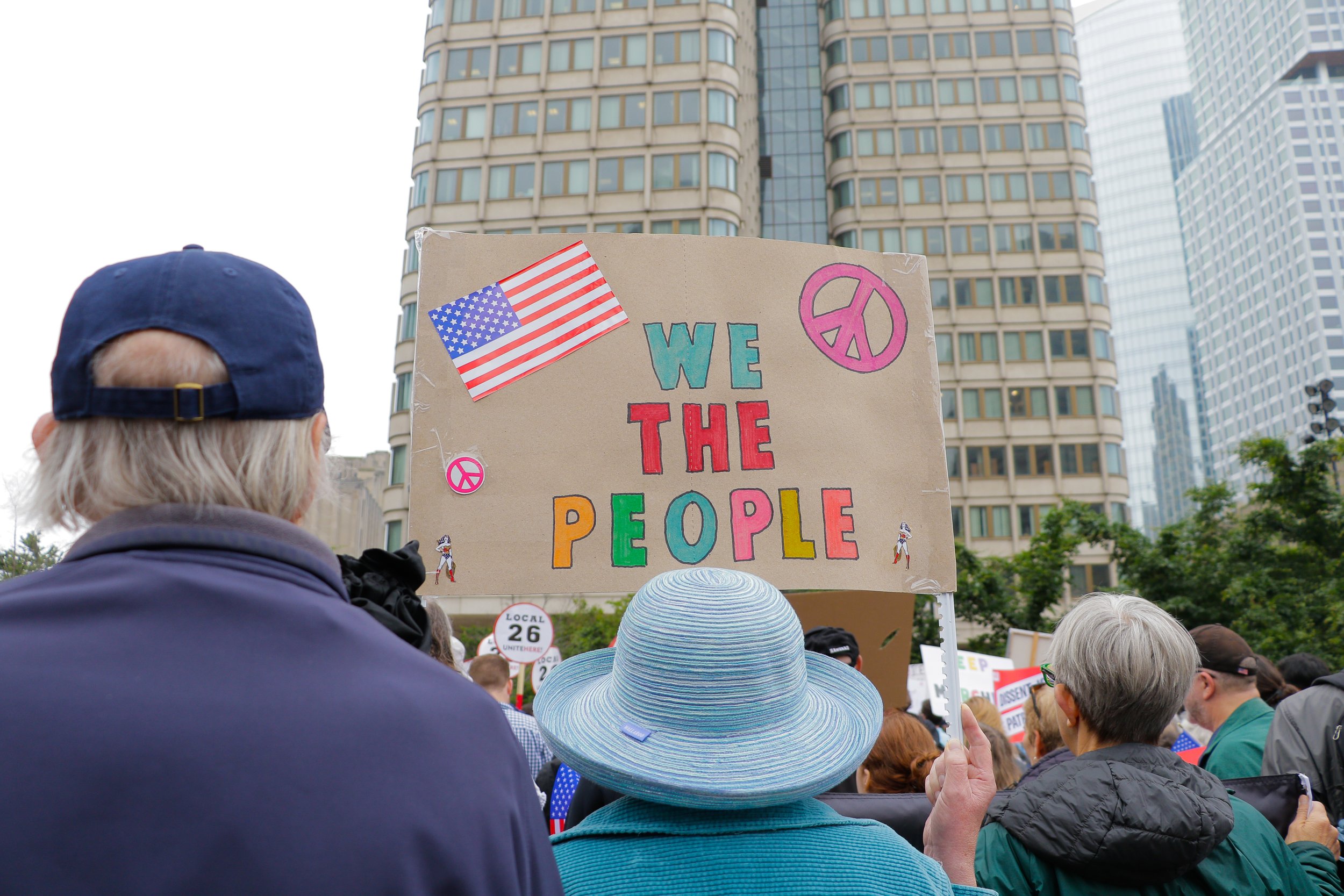 A person holding a sign saying “We the people” amidst a crowd of protestors.