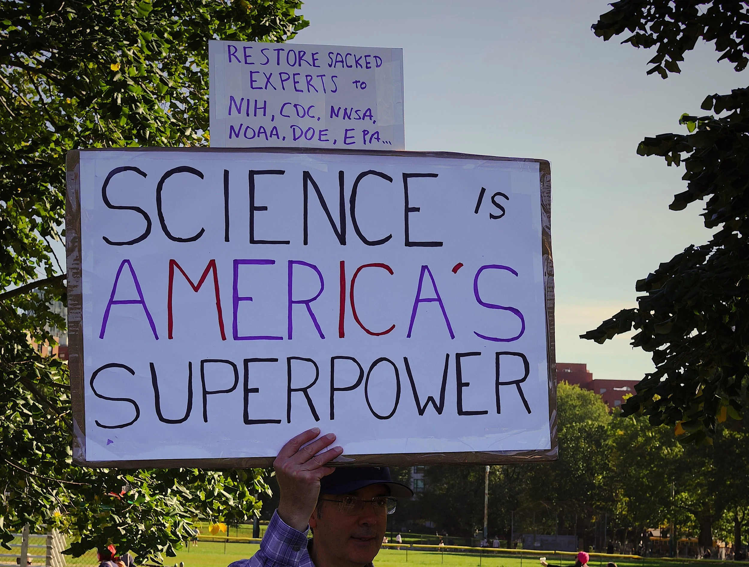 protest sign saying "Restore sacked experts to NIH, CDC, NNSA, NOAA, DOE, EPA..." and "Science is America's Superpower"