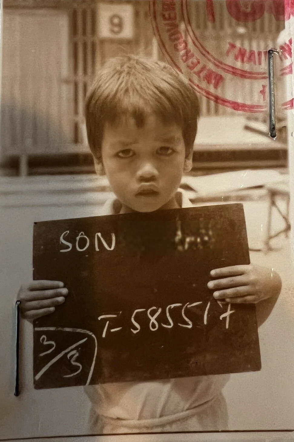 A photograph of a small boy holding a chalk board saying “Son” and a series of numbers.