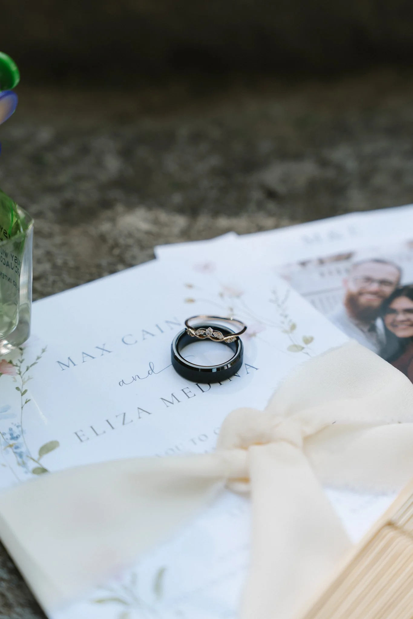Wedding rings placed on a wedding program with floral decorations and a photograph of a couple.