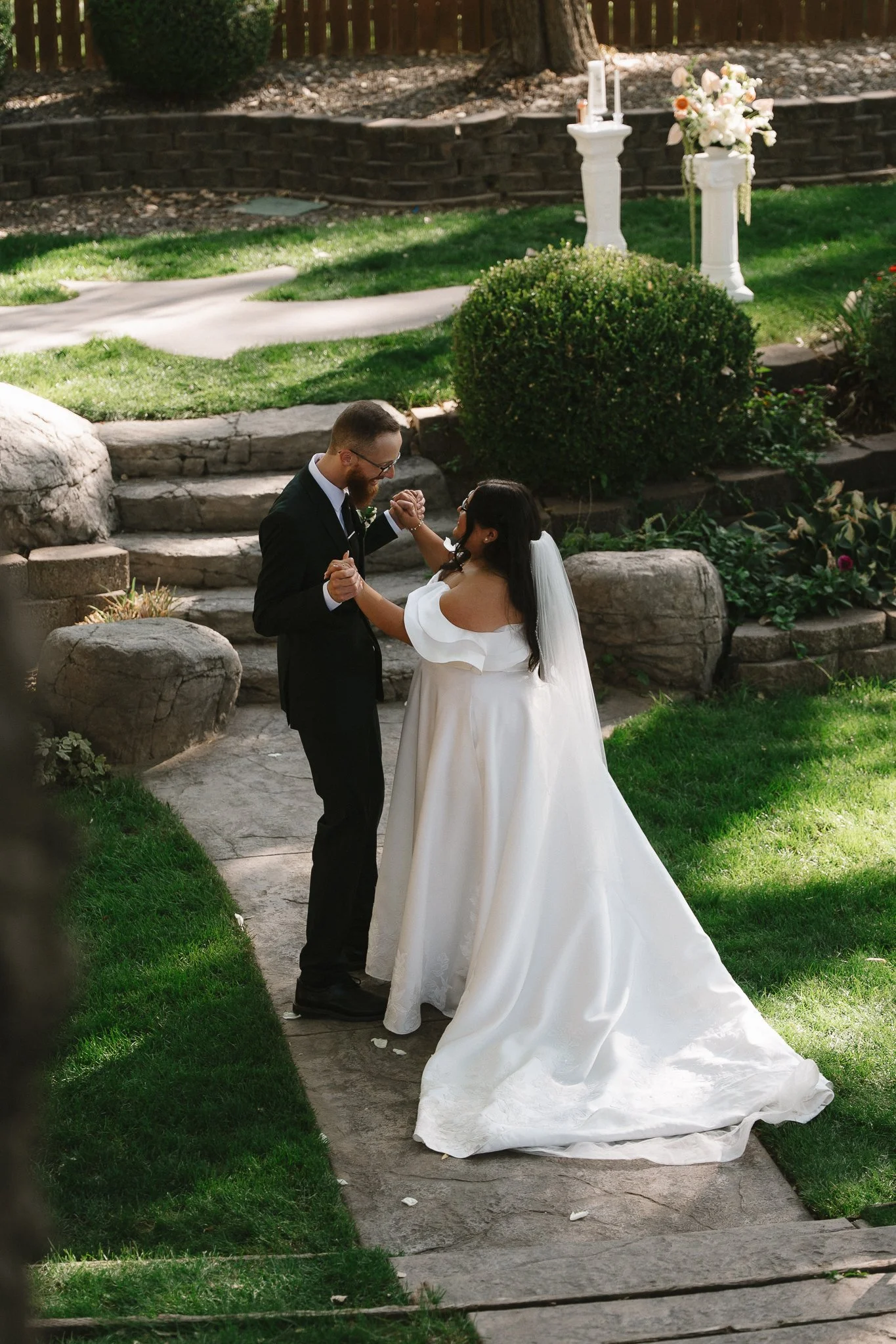 Bride and groom dancing outdoors in a garden during their wedding ceremony.