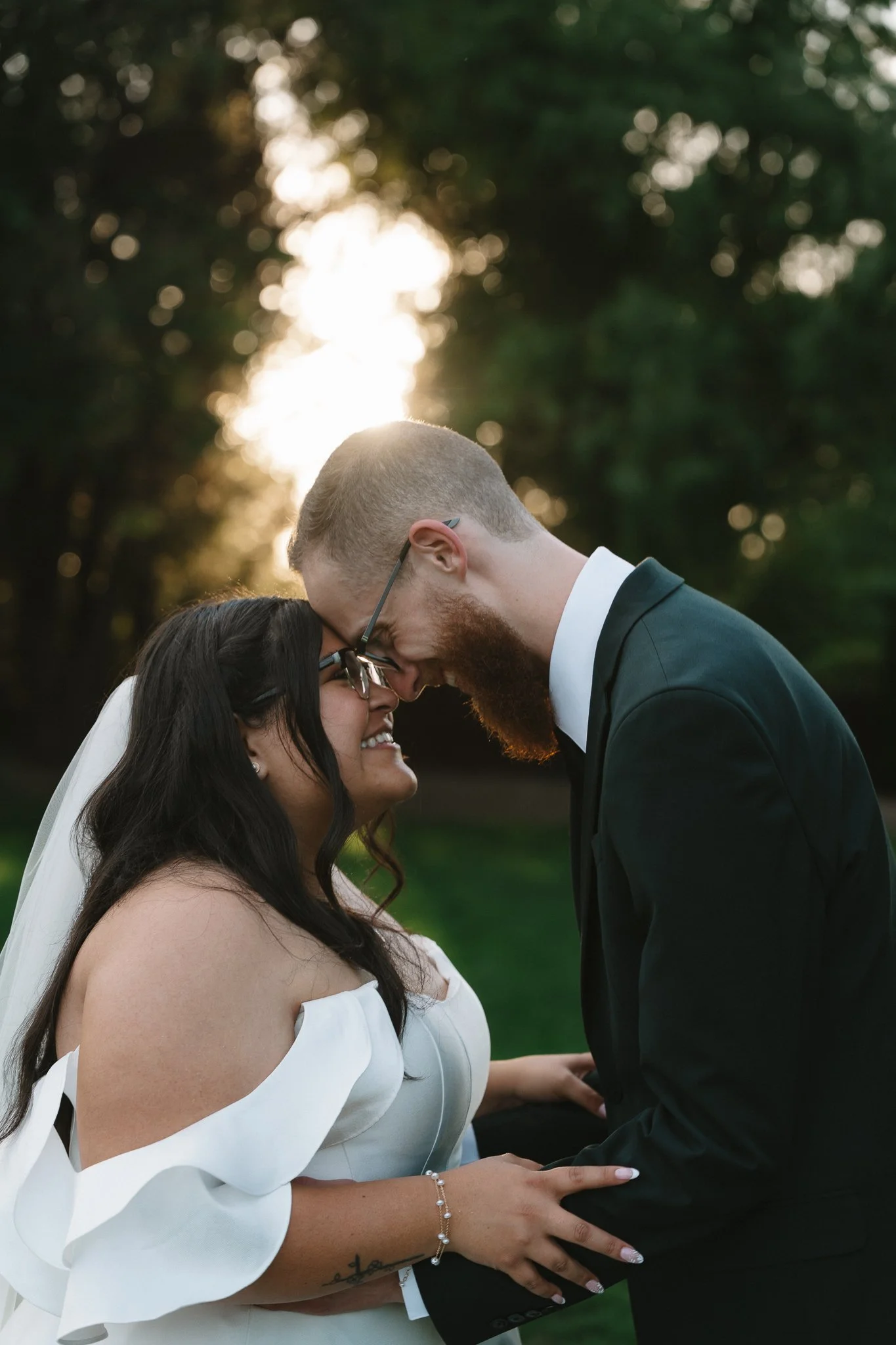 A couple touching foreheads during a wedding ceremony outdoors at sunset.