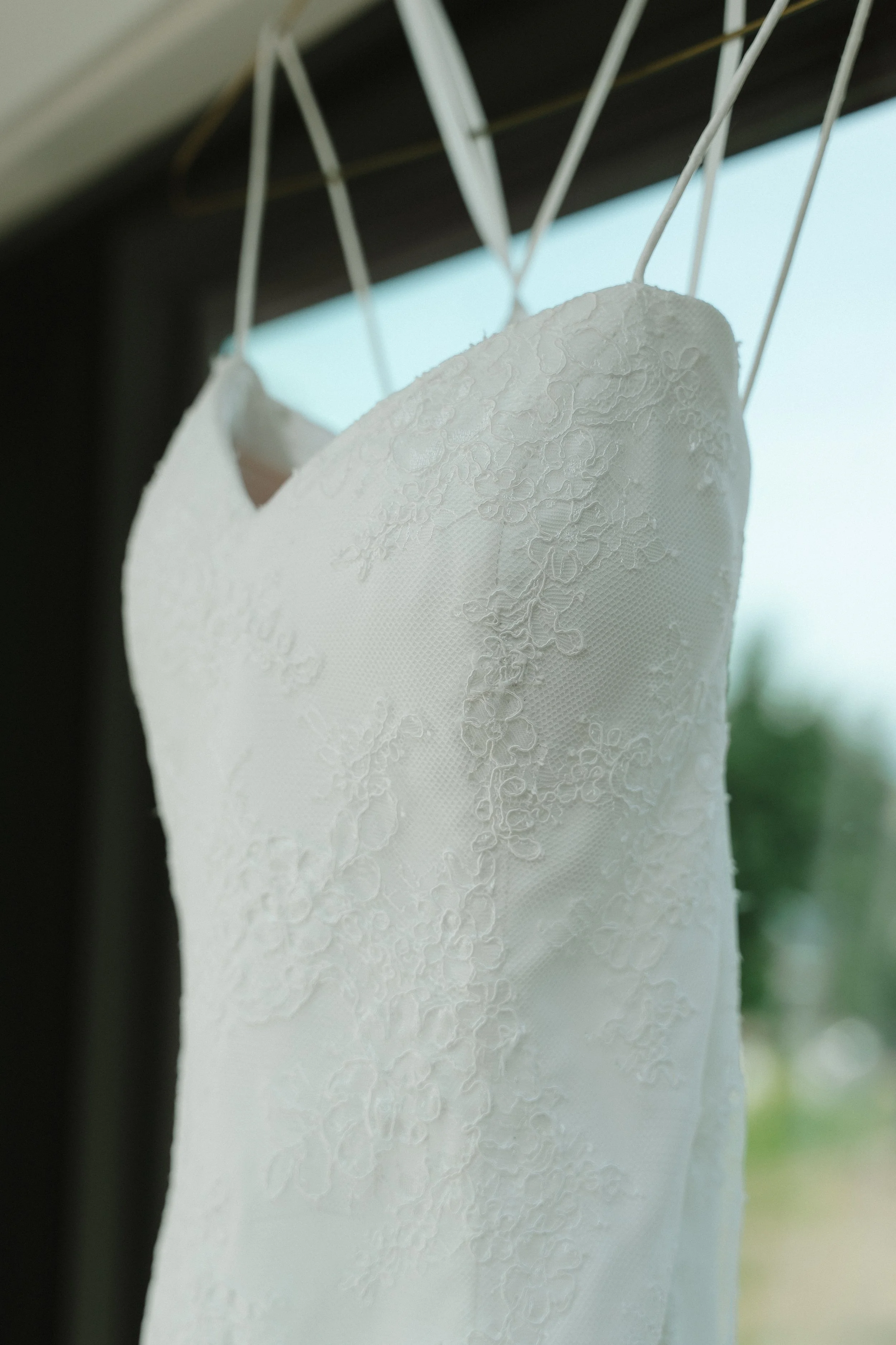 Close-up of a white wedding dress hanging on a hanger.
