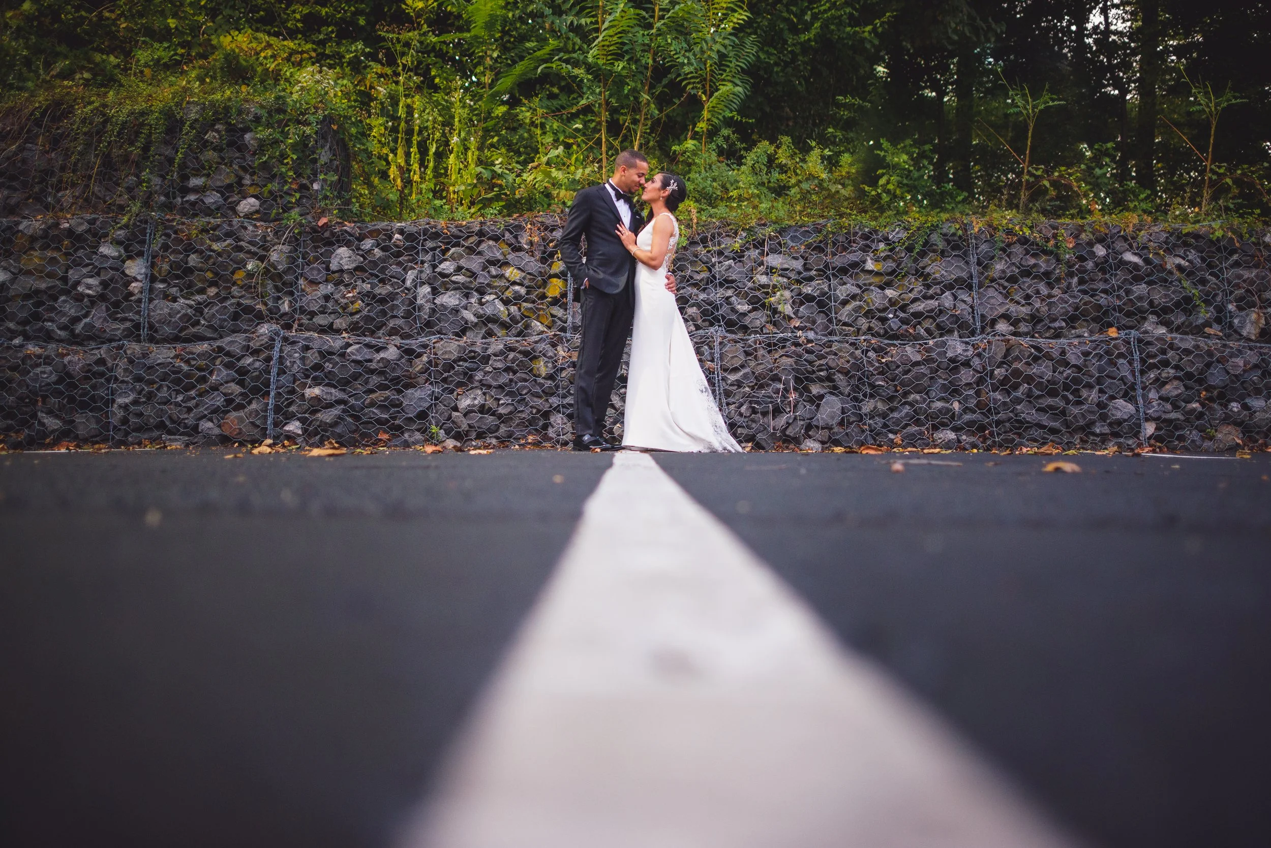 Bride and groom on road with stone wall background