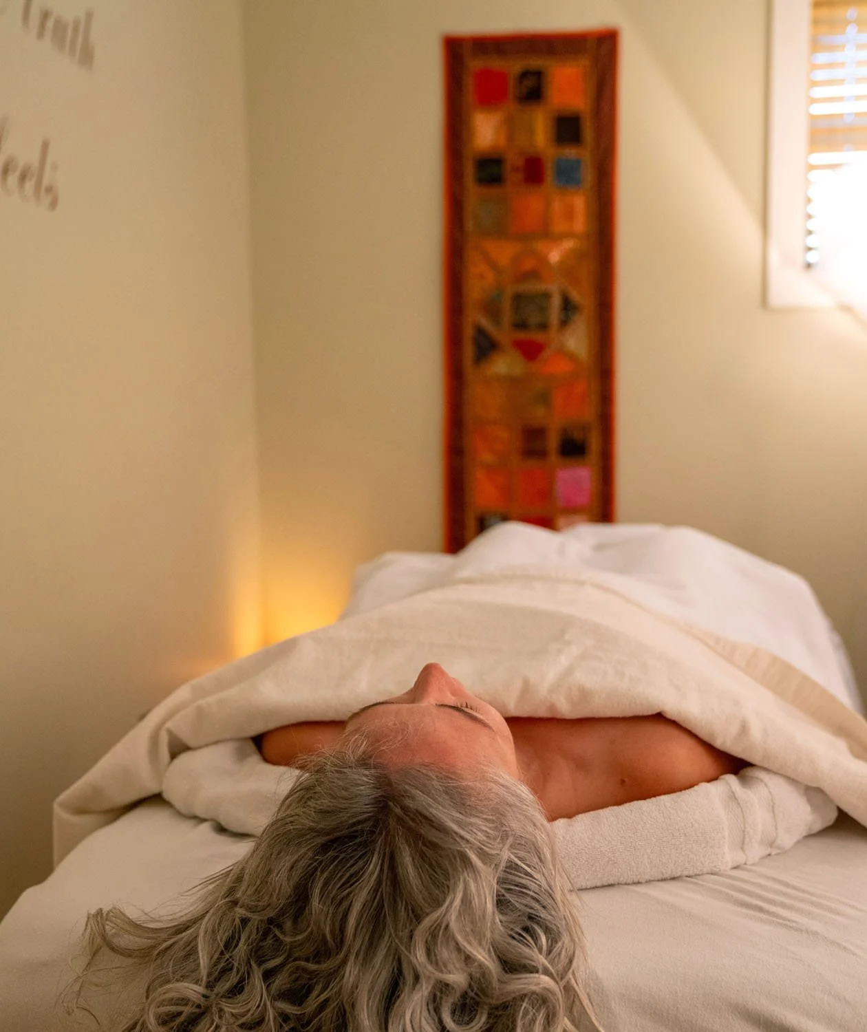 woman lying on massage table relaxing under blankets