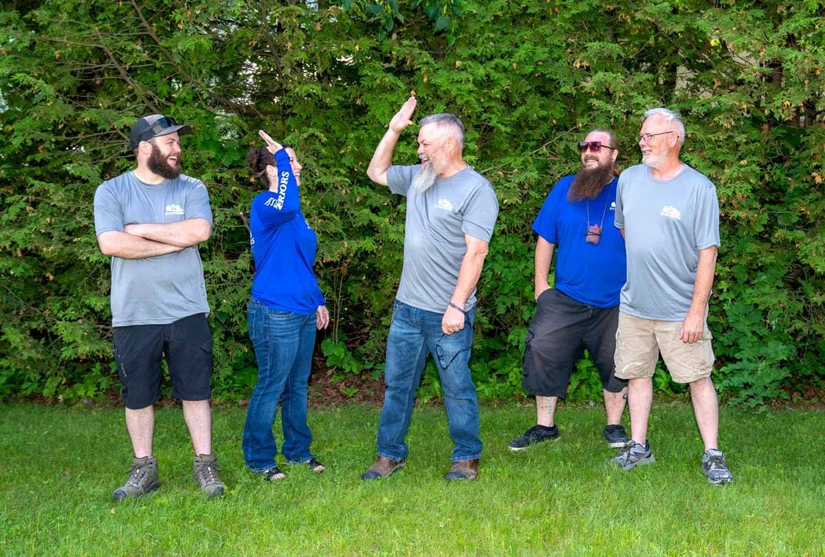 a team of five colleagues standing outside, two are giving a high five