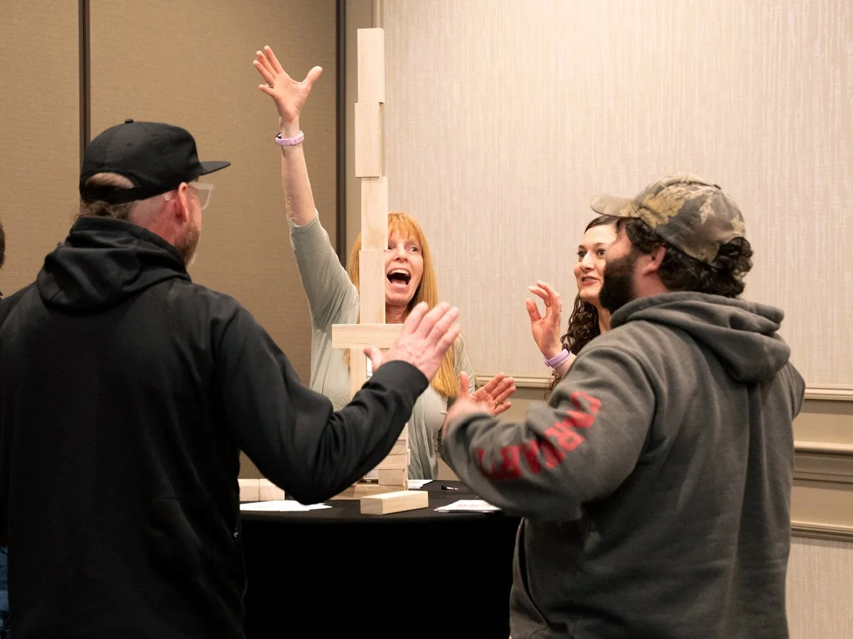 team of four colleagues are joyous from successfully stacking wooden blocks in the form of a tower