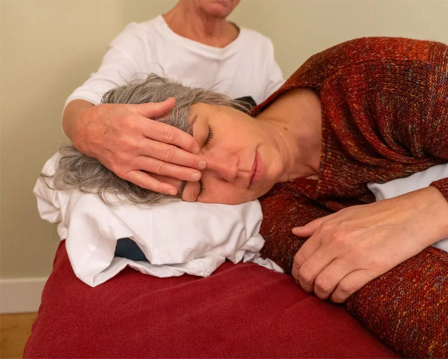 massage therapist is doing cranial sacral therapy for her client on her face
