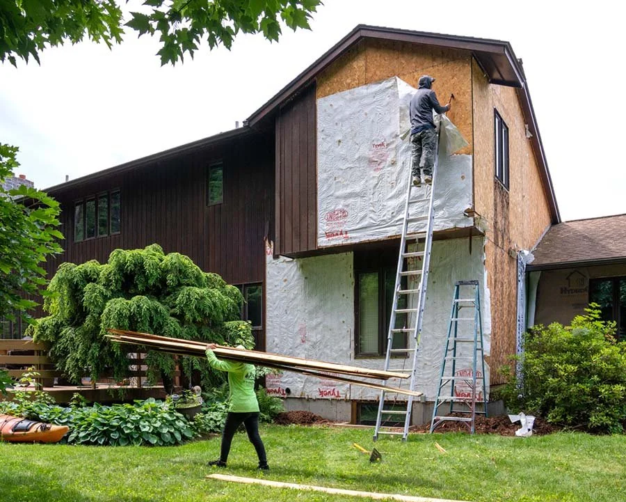 two workers at a house renovation replacing the siding