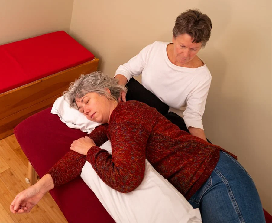 massage therapist is seated and treating a client