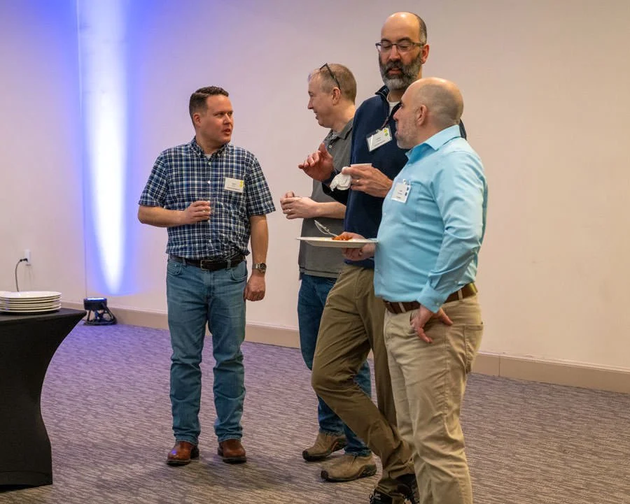 four male colleagues talking at a conference