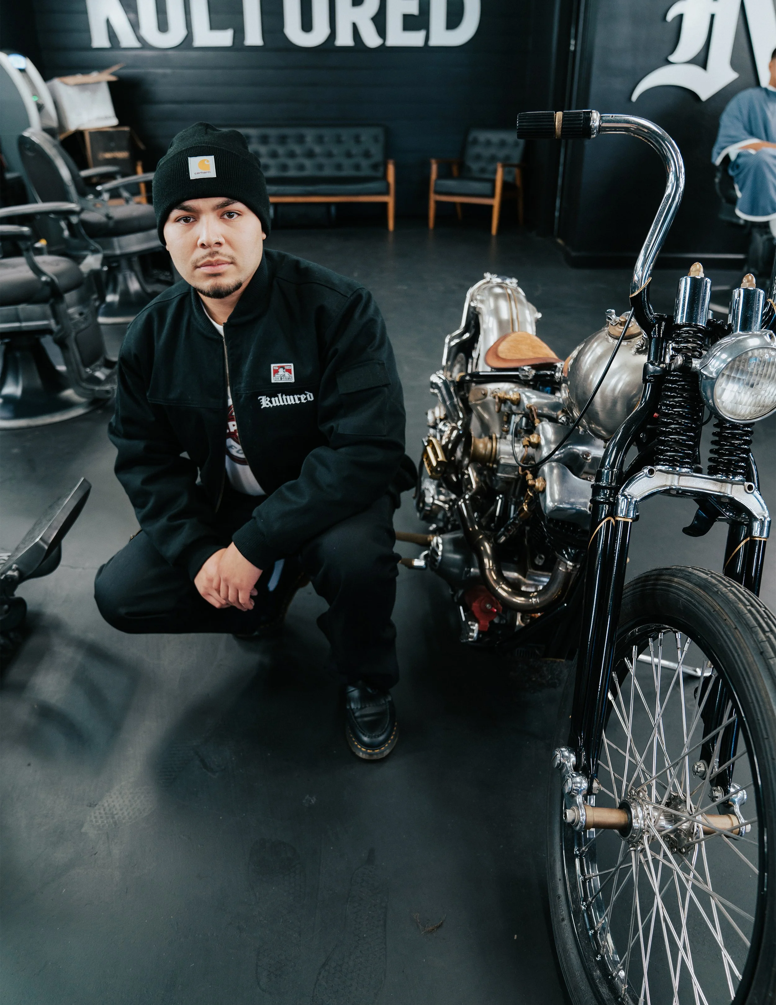 Barber trimming a client's beard with clippers in a barbershop.