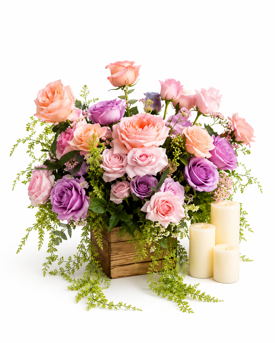 Artificial floral arrangement with blush pink, lavender, and peach roses, cascading greenery, and three ivory pillar candles on a white background.
