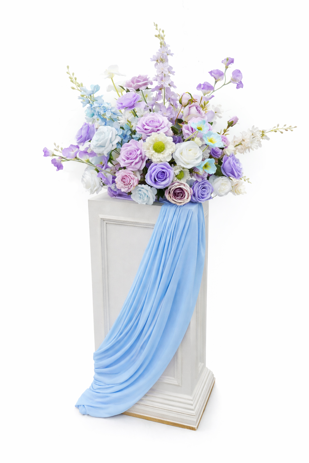 Tall white pedestal pillar topped with a soft pastel floral arrangement featuring lavender, light blue, and white flowers with greenery—ideal for wedding aisles, ceremony entrances, and elegant event décor.