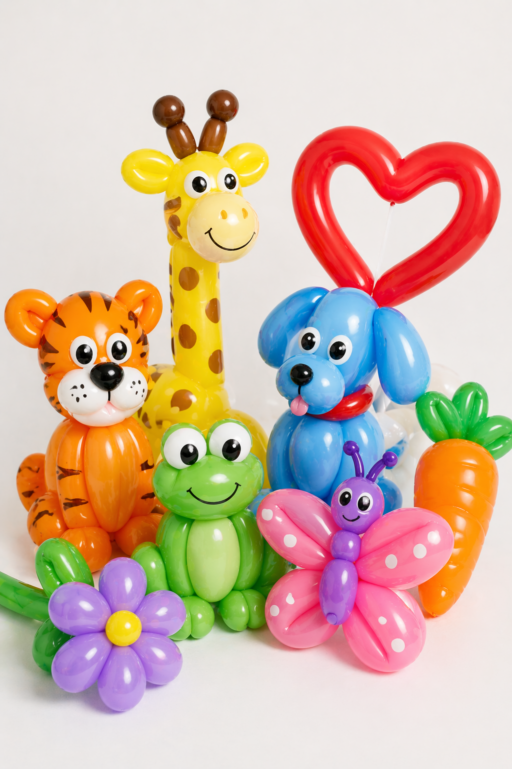 Bright collection of balloon twisting animals including a dog, giraffe, tiger, frog, butterfly, and heart design on a clean white background, showcasing fun party entertainment options.