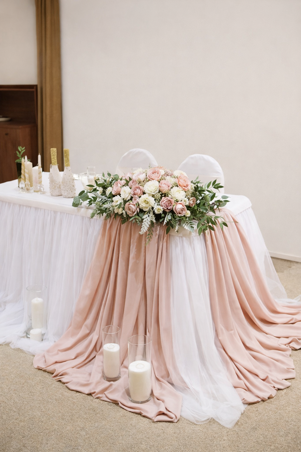 Blush pink and white sweetheart table draping with lush floral centerpiece, greenery, and candles for a romantic wedding head table design.