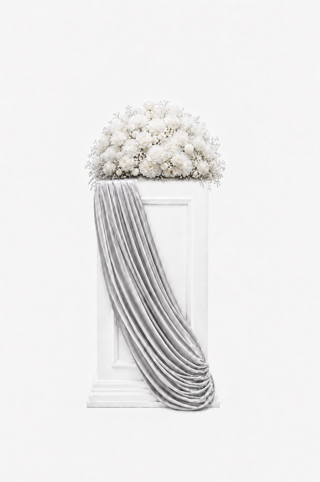 All-white floral arrangement displayed on a white pedestal with elegant silver draping.