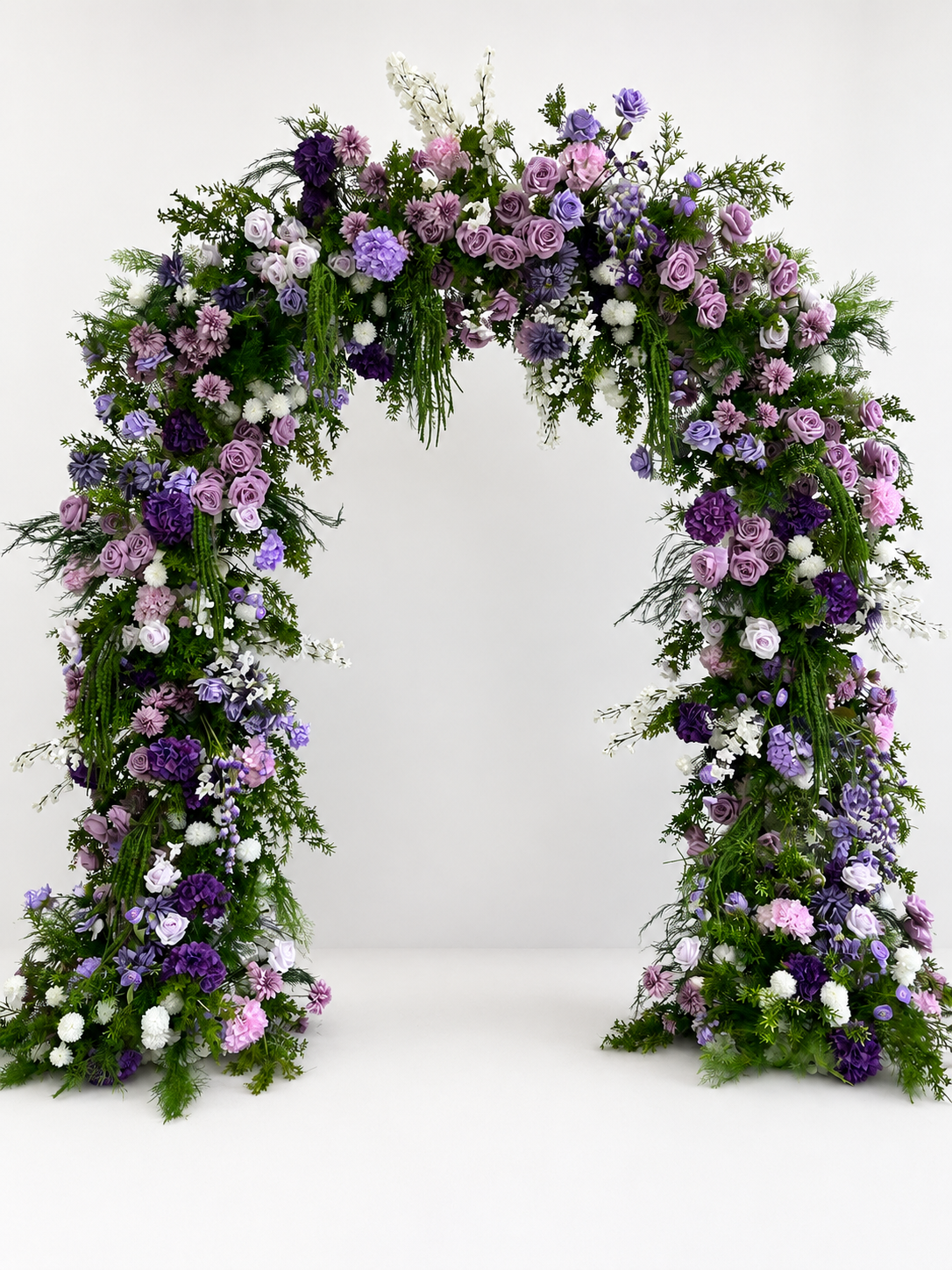 Purple floral wedding arch decorated with lavender roses, hydrangeas, white blossoms, and cascading greenery.