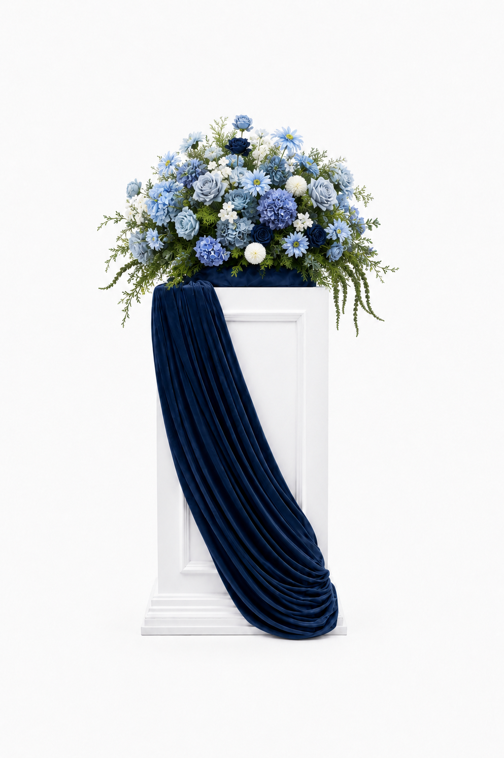 Blue floral arrangement with roses, hydrangeas, daisies, and greenery displayed with navy draping.