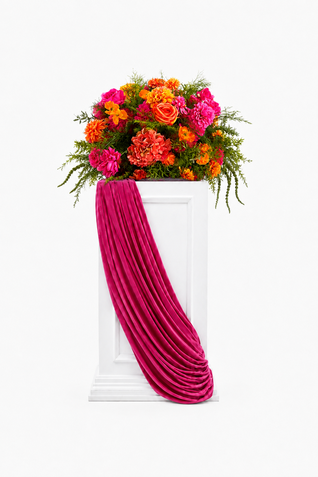 Pink and orange floral arrangement displayed on a white pedestal with fuchsia velvet draping.