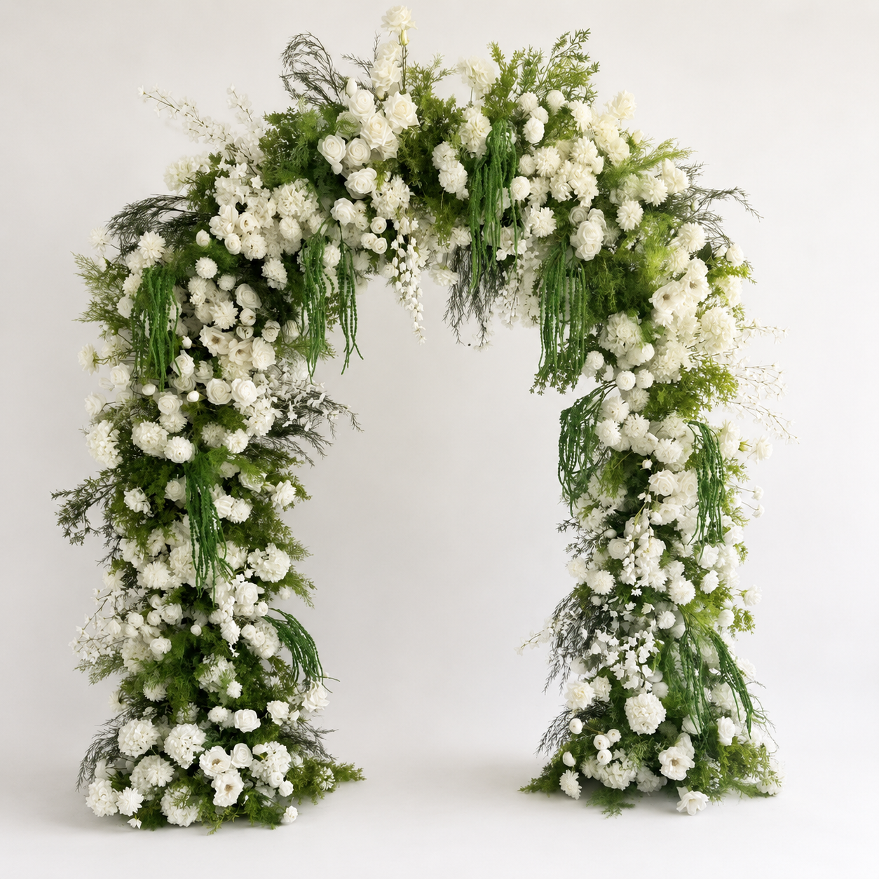 White floral wedding arch covered with white roses, hydrangeas, chrysanthemums, and cascading greenery.