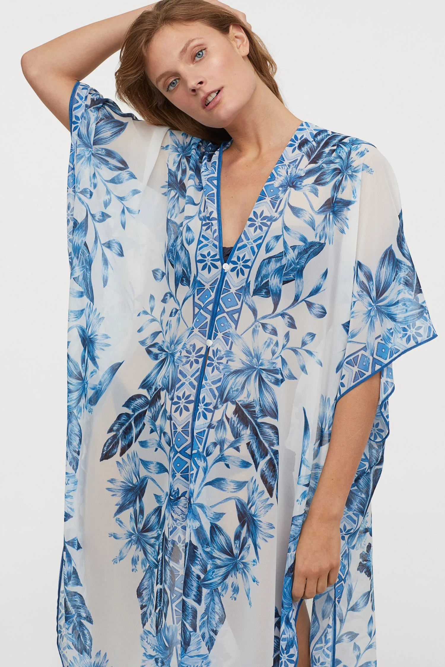 Woman wearing a white and blue floral kaftan with short sleeves and a button-down front.