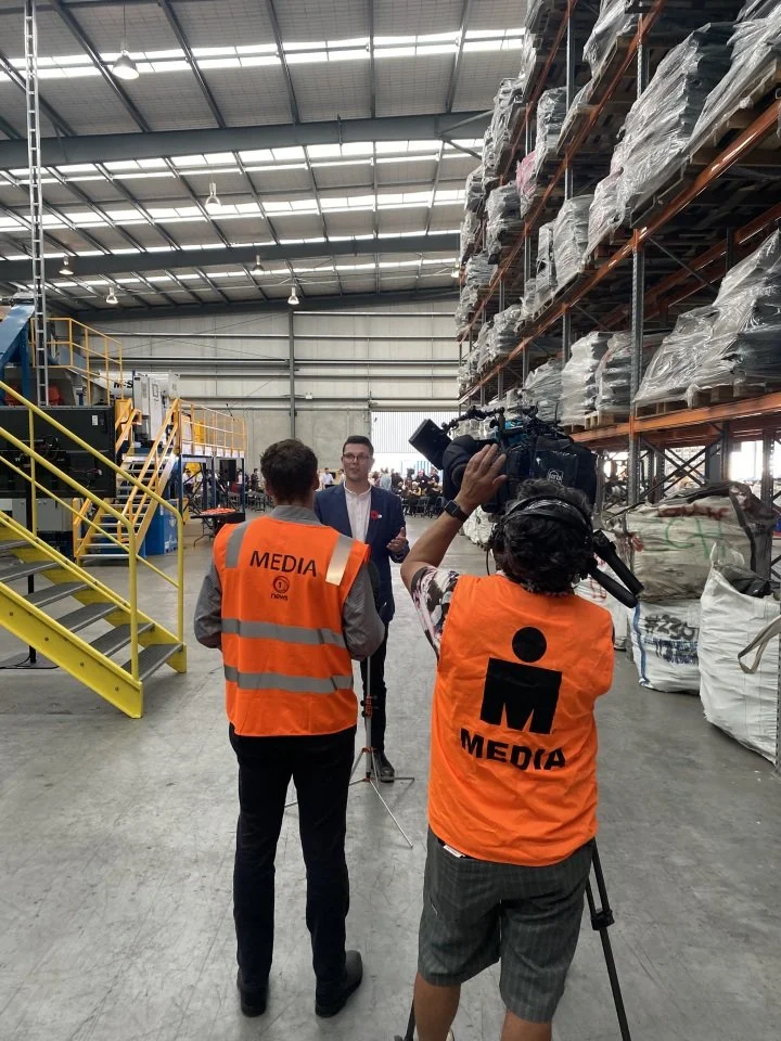 A Pead client conducting an interview with the media, standing inside of a corporate warehouse environment.