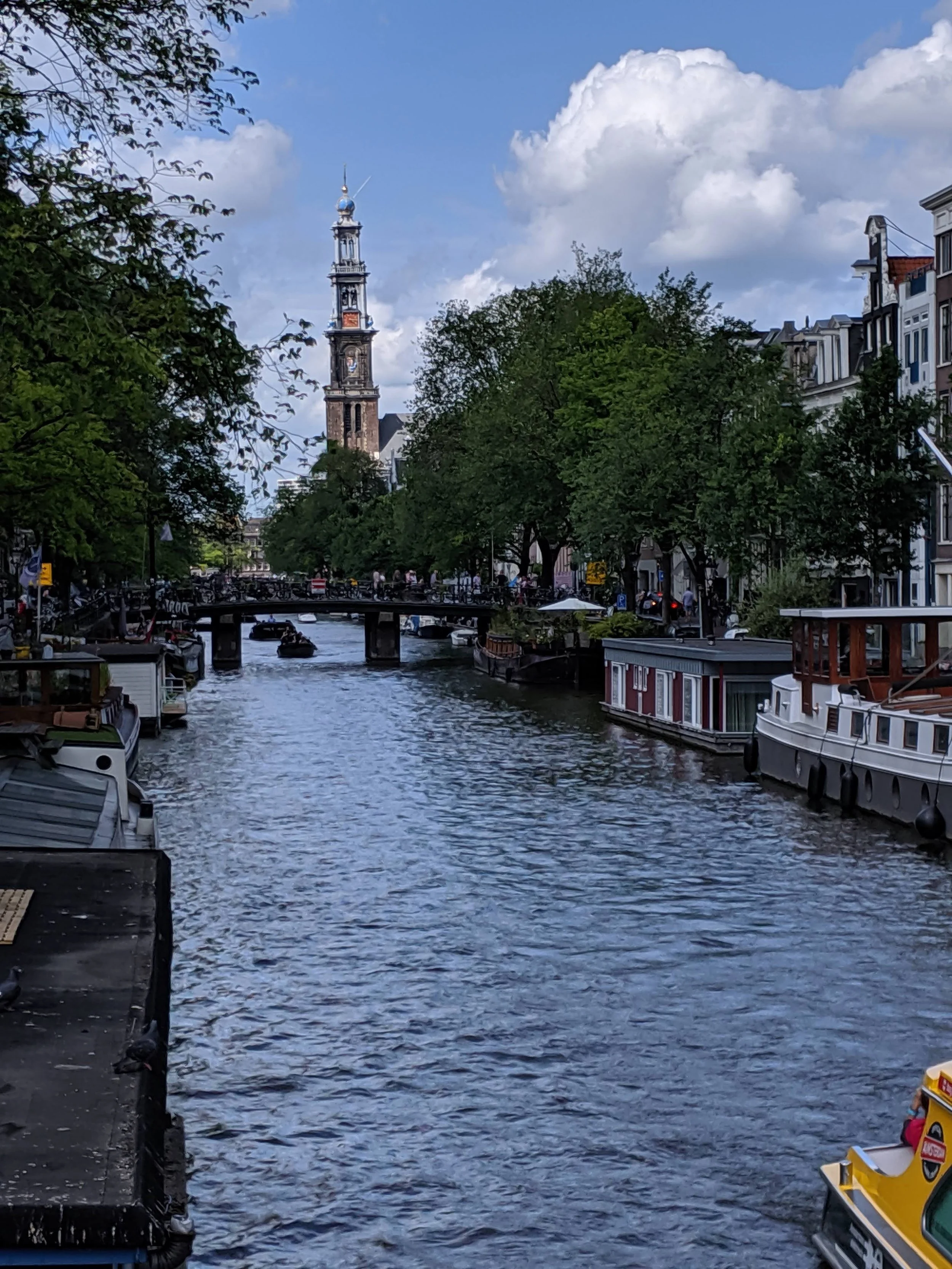 canal in Amsterdam with a bridge and tower in the distance