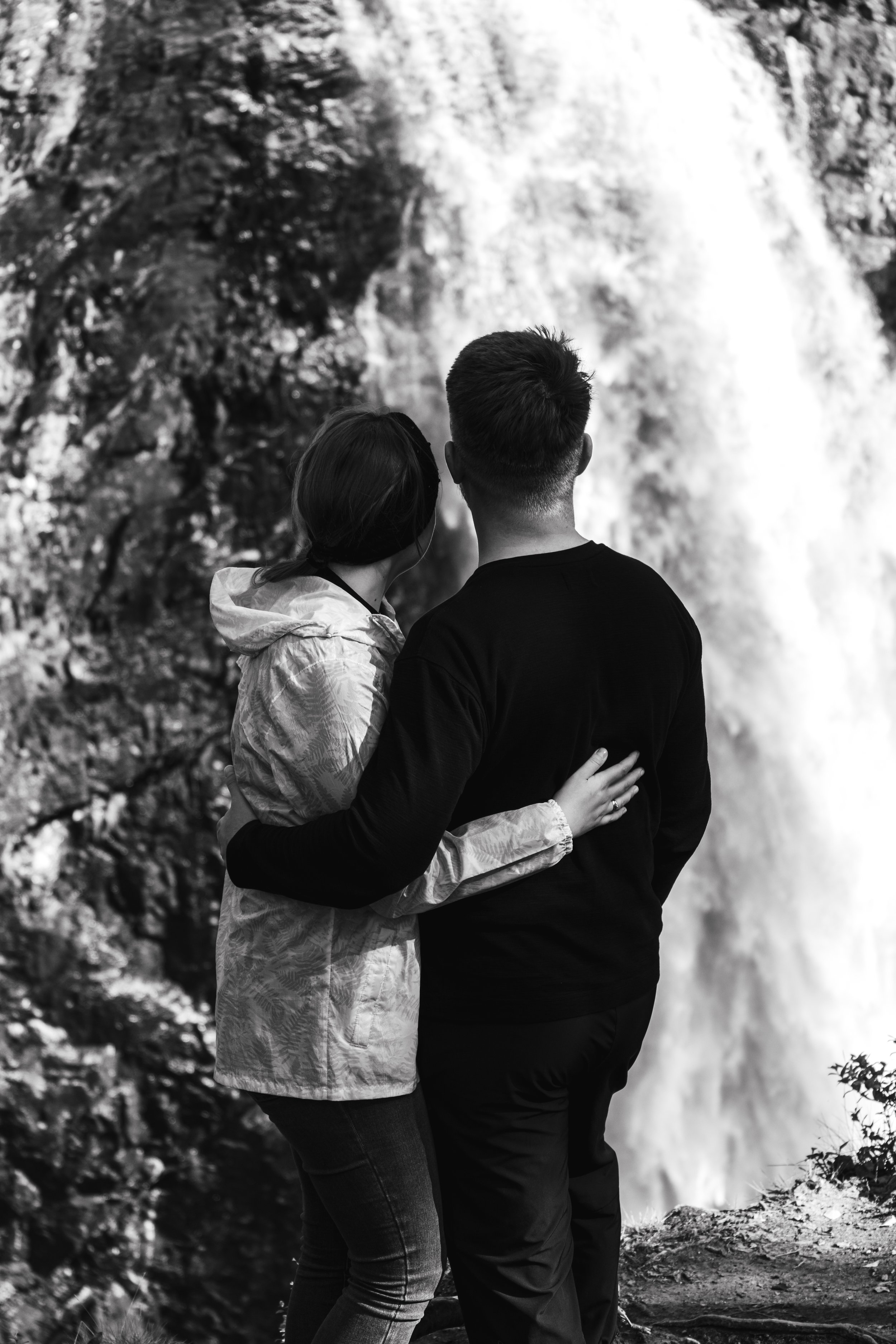 Couple embracing while looking at a waterfall