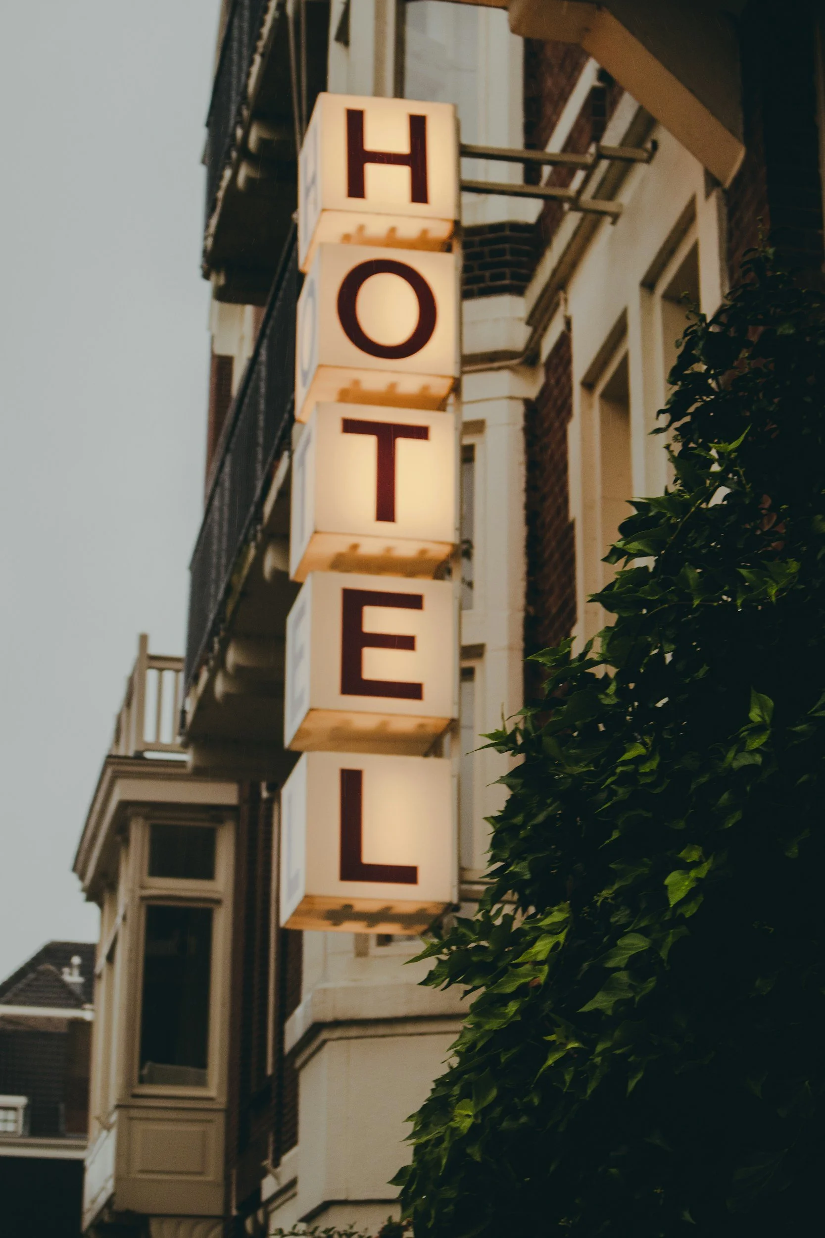 Building with a lit sign that spells out 'HOTEL' with illuminated letters, visible at dusk or evening.