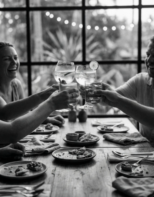 People clinking glasses with drinks at a dining table in a restaurant.