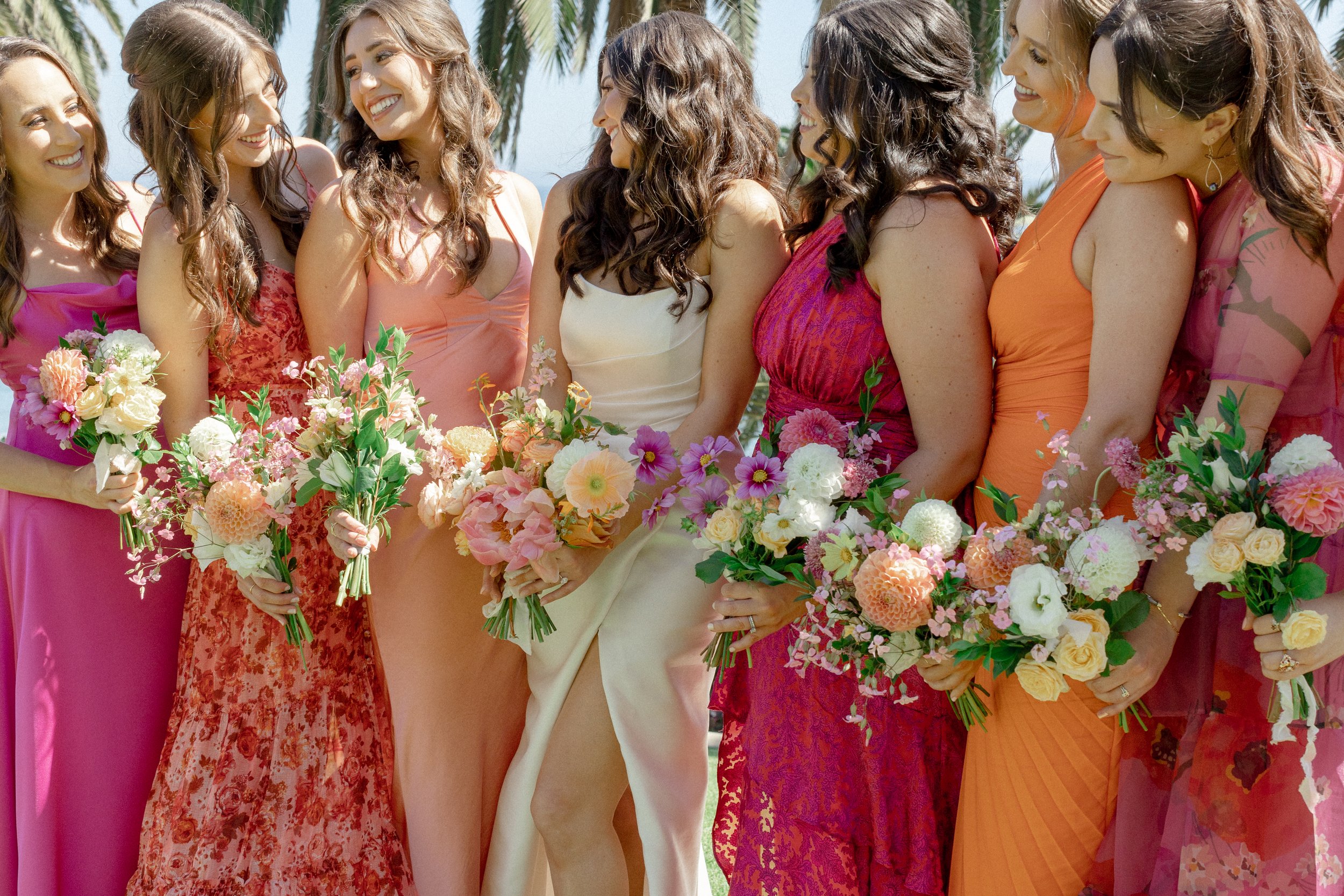 bride and bridesmaids holding colorful flower bouquets