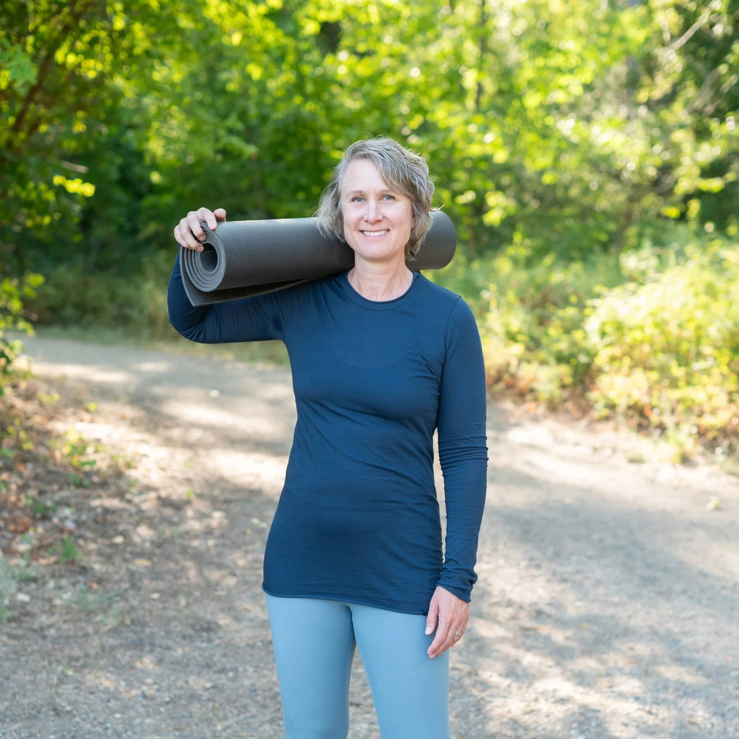 Joanna dunn yoga wearing blue workout clothes with yoga mat on shoulder