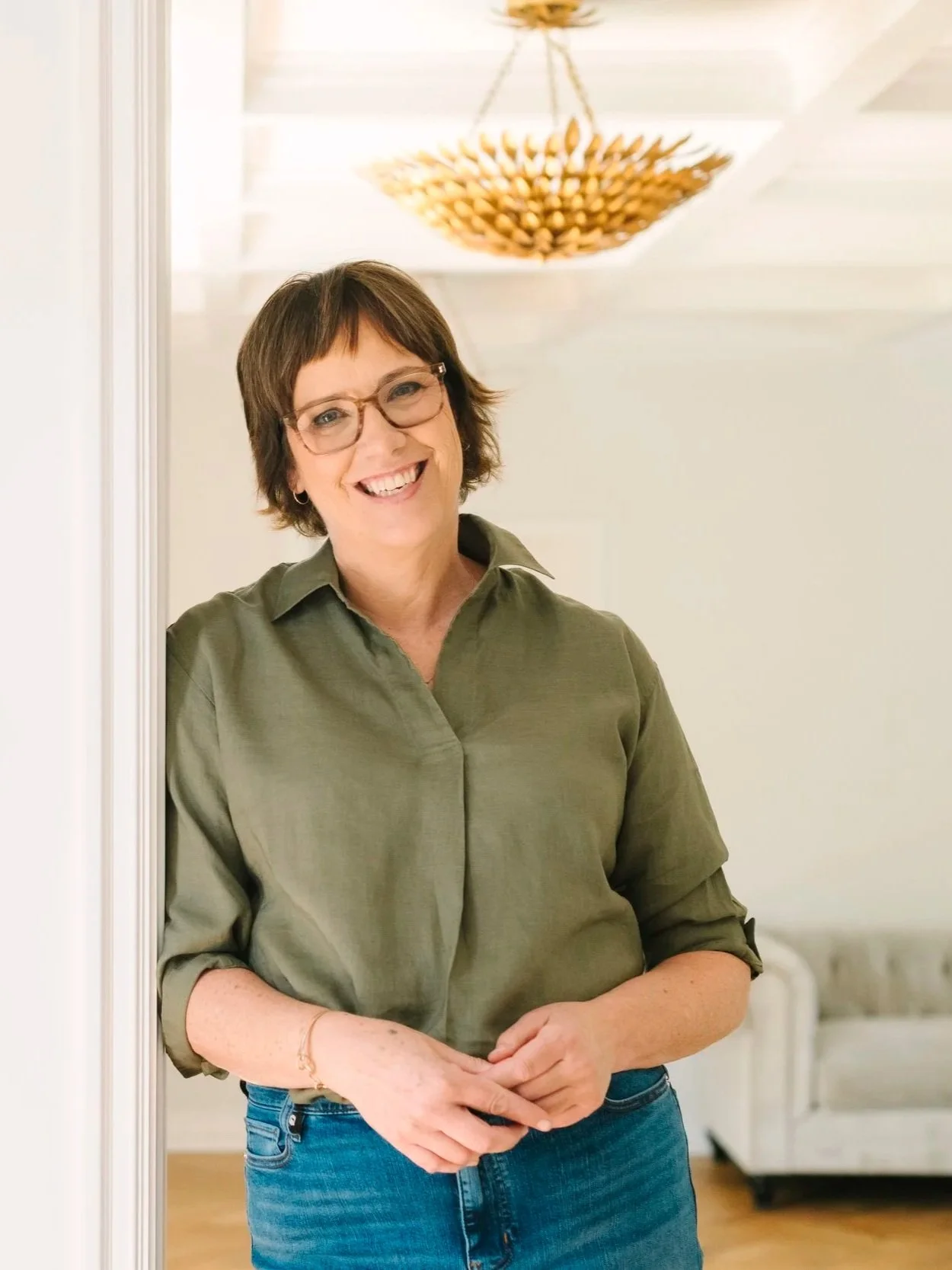 woman wearing green shirt leaning against doorway