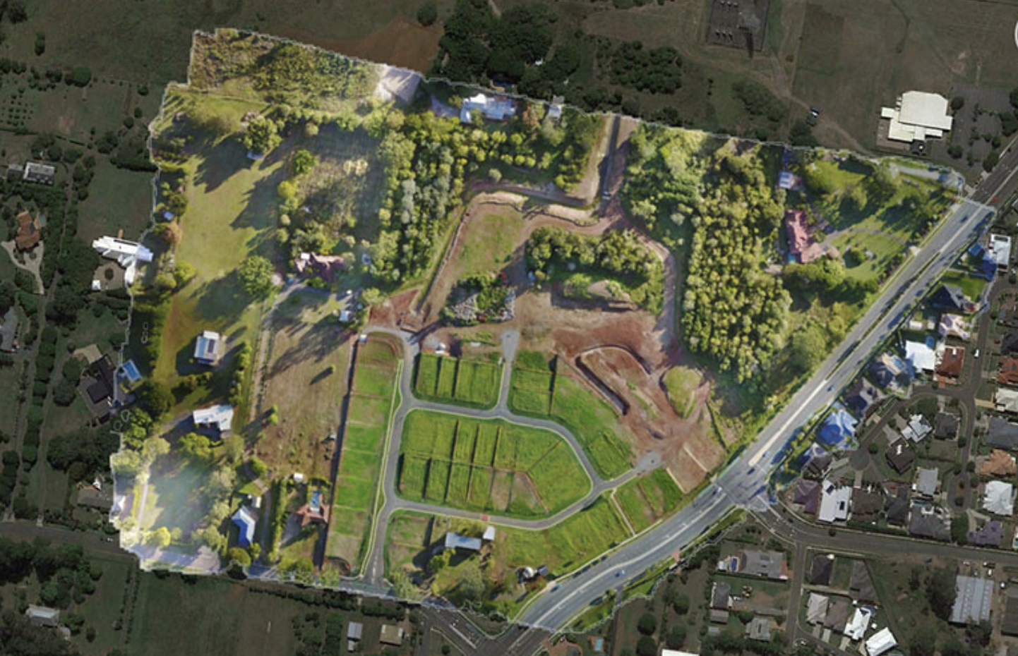 Aerial view of a suburban area with green spaces, roads, and houses. The image shows a mix of developed residential areas and undeveloped land with trees. Orthomosiac map generated from drone images showing photogrammetry application