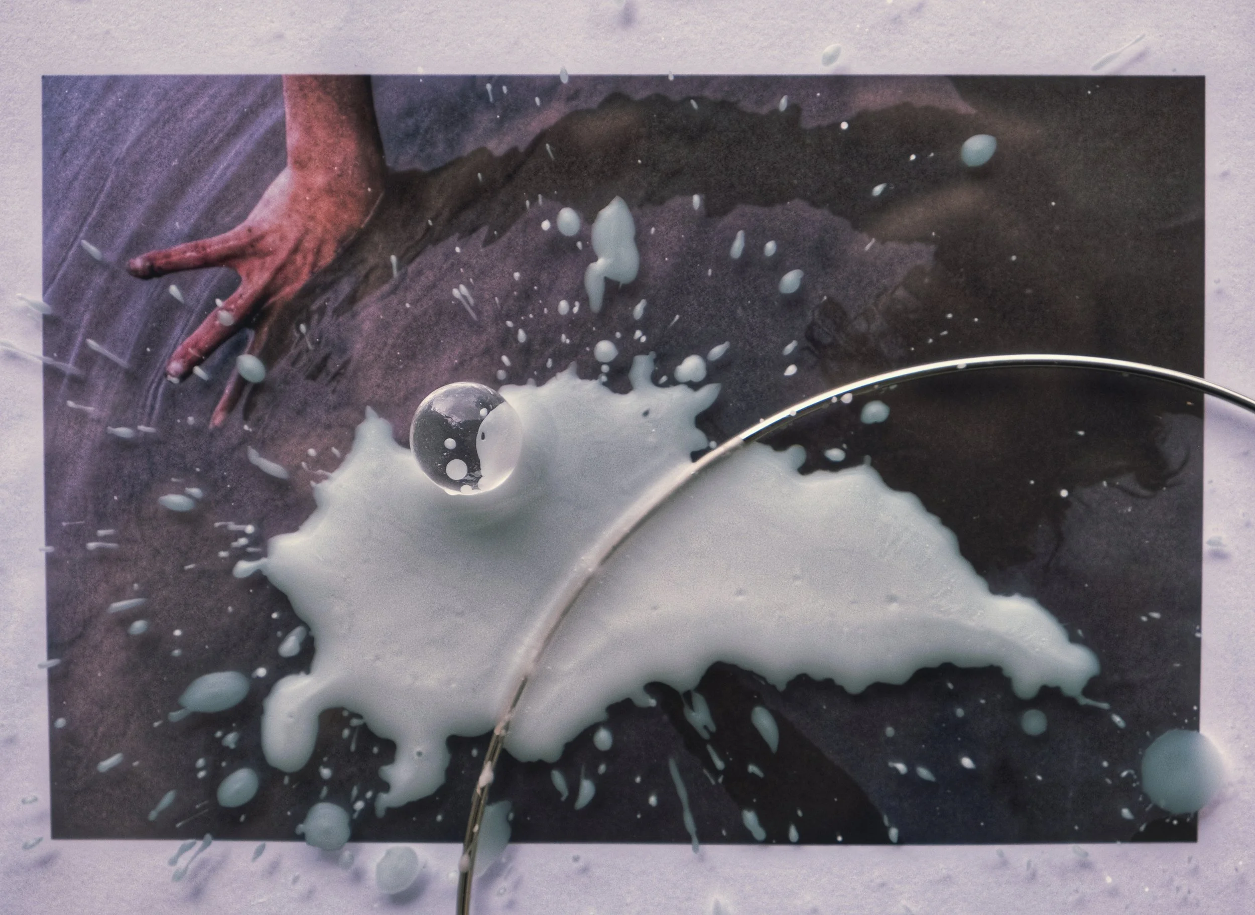 A close-up of a painting with a hand reaching out, accompanied by splashes of white paint and a metallic arc across the lower right.